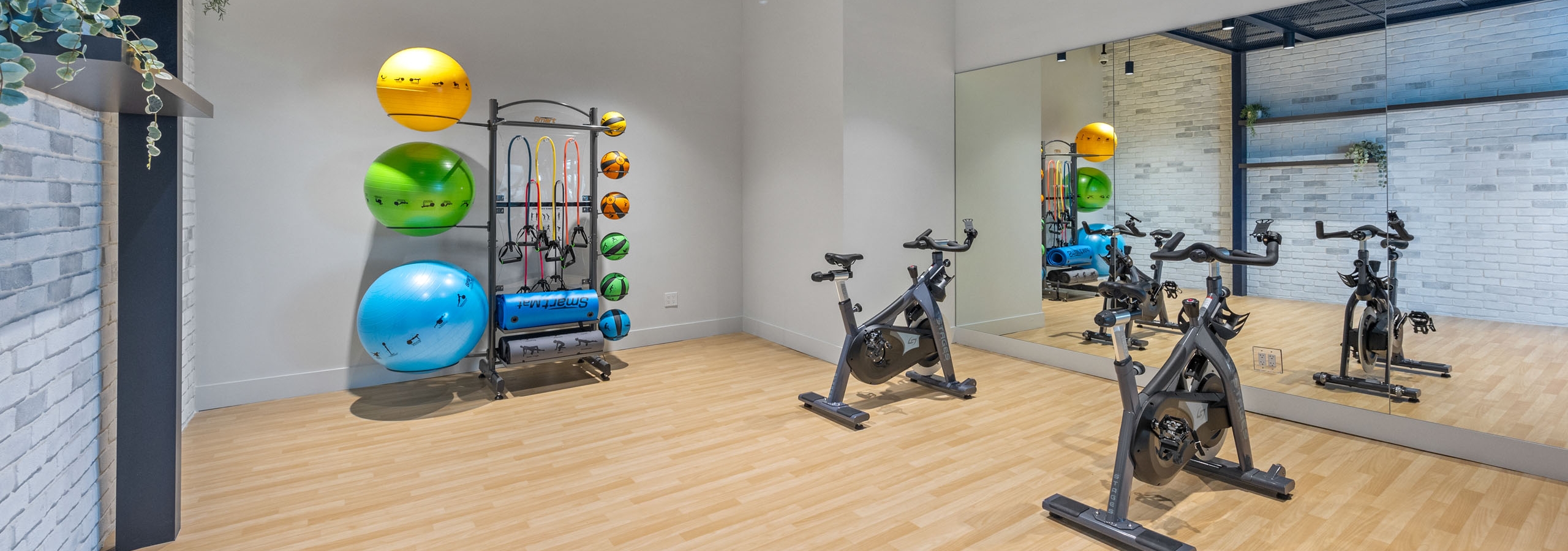 A bright yoga and spin cycle room at AMLI Wynwood with bamboo floors and wall length mirrors showing two bicycles