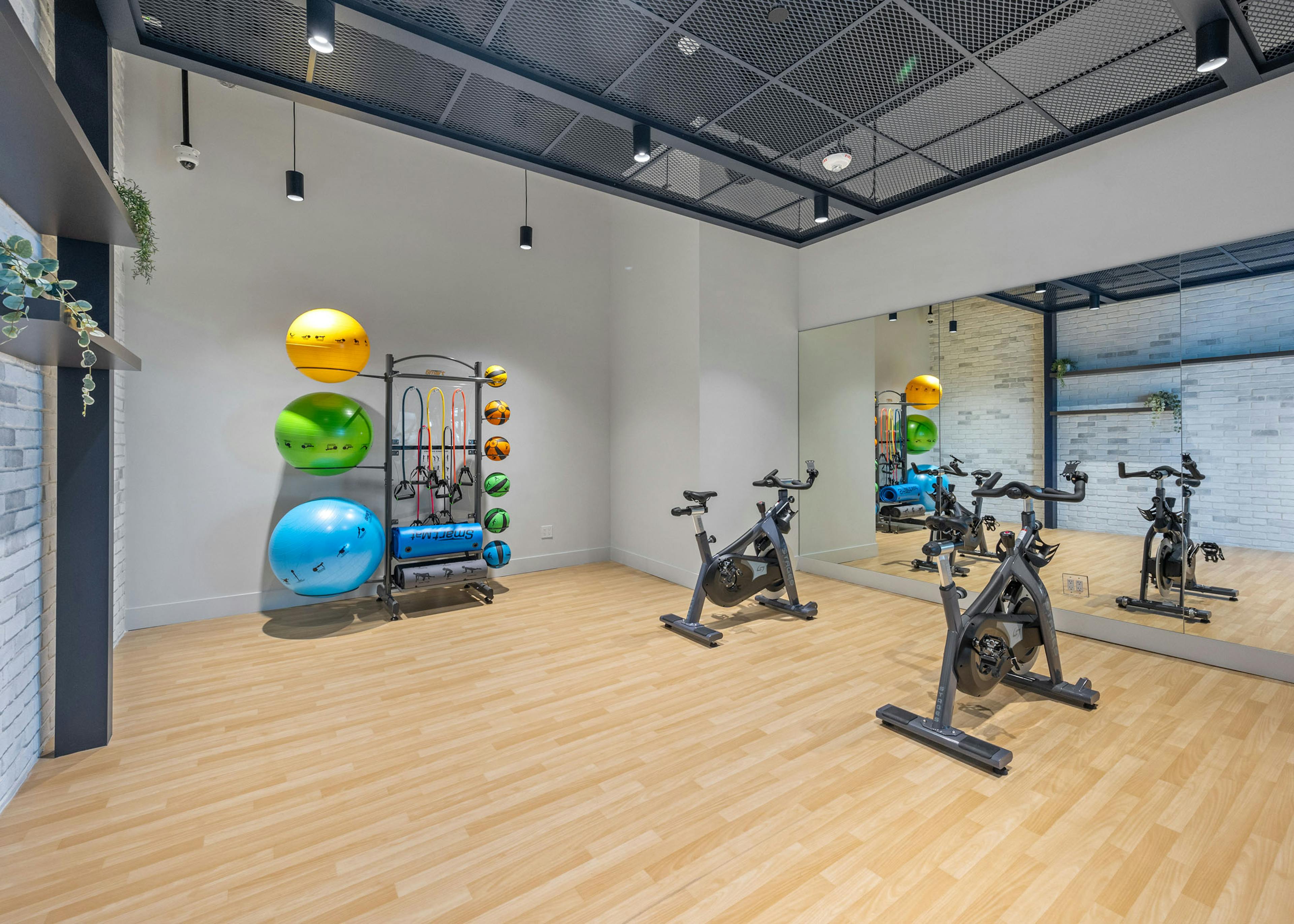 A bright yoga and spin cycle room at AMLI Wynwood with bamboo floors and wall length mirrors showing two bicycles