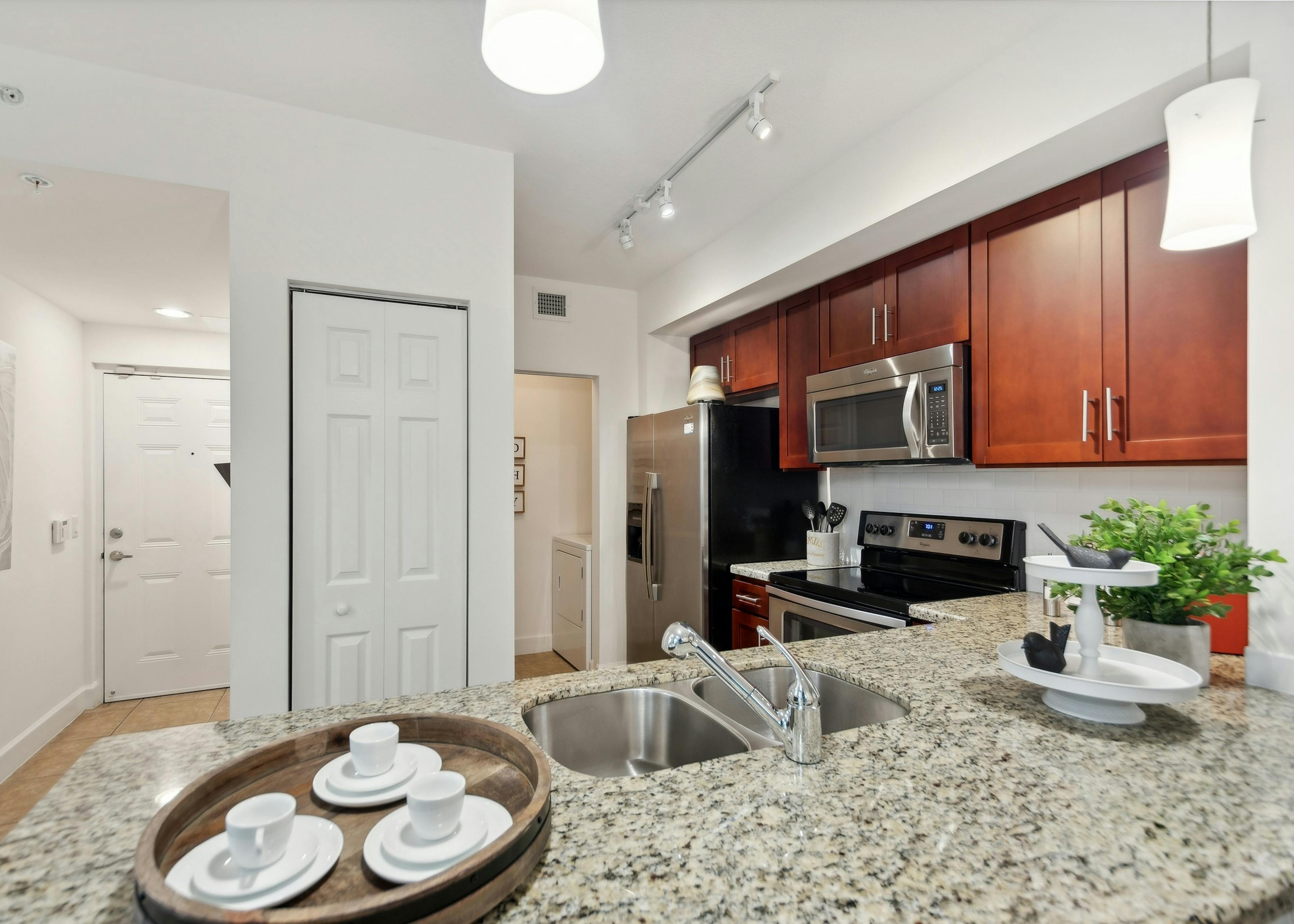 Open kitchen at AMLI Toscana Place apartments with a granite counter and stainless steel appliances set into cherry cabinets