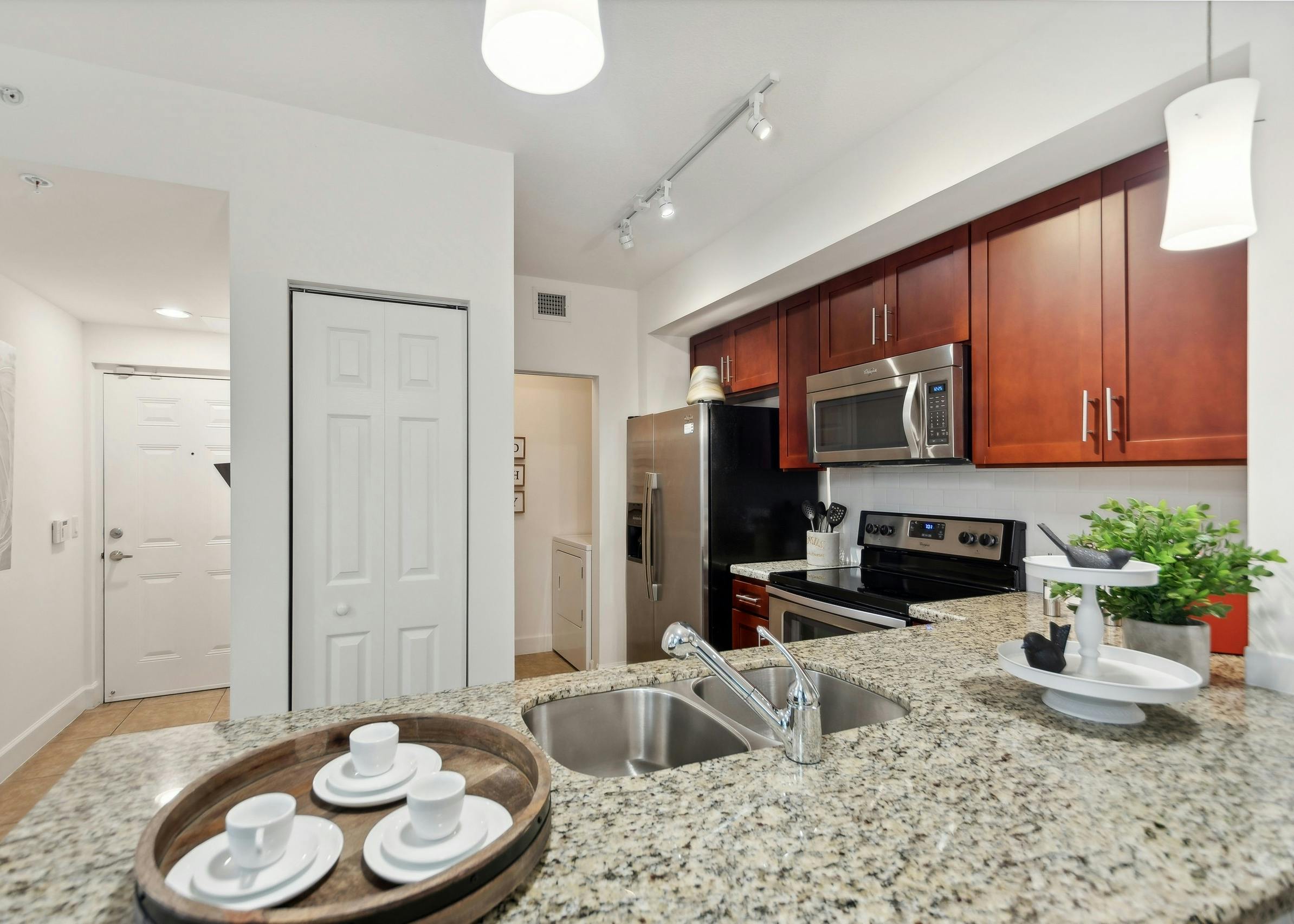 Open kitchen at AMLI Toscana Place apartments with a granite counter and stainless steel appliances set into cherry cabinets