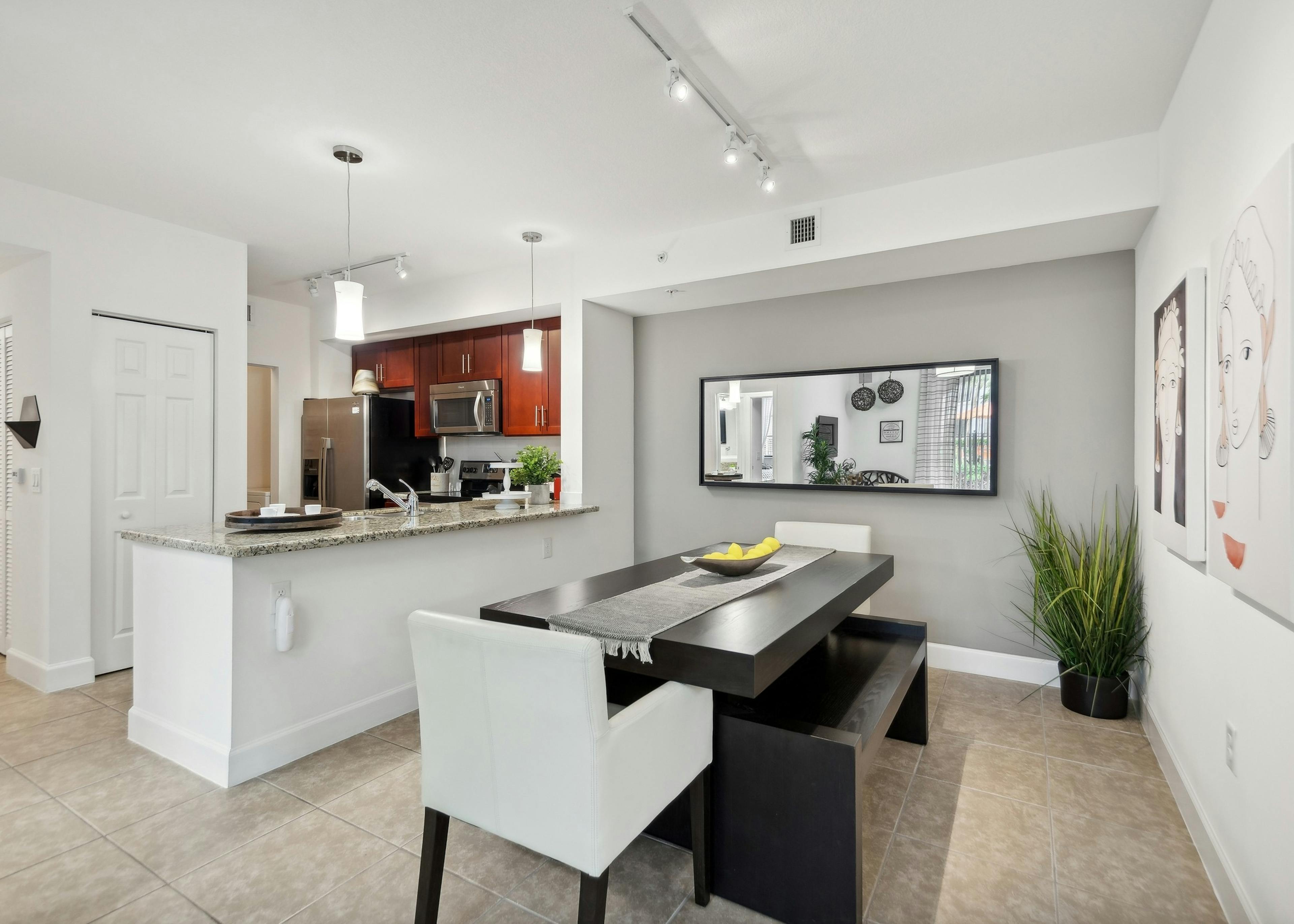 Dining room at AMLI Toscana Place apartments with a dining table looking into a kitchen with cherry cabinets and stainless steel appliances