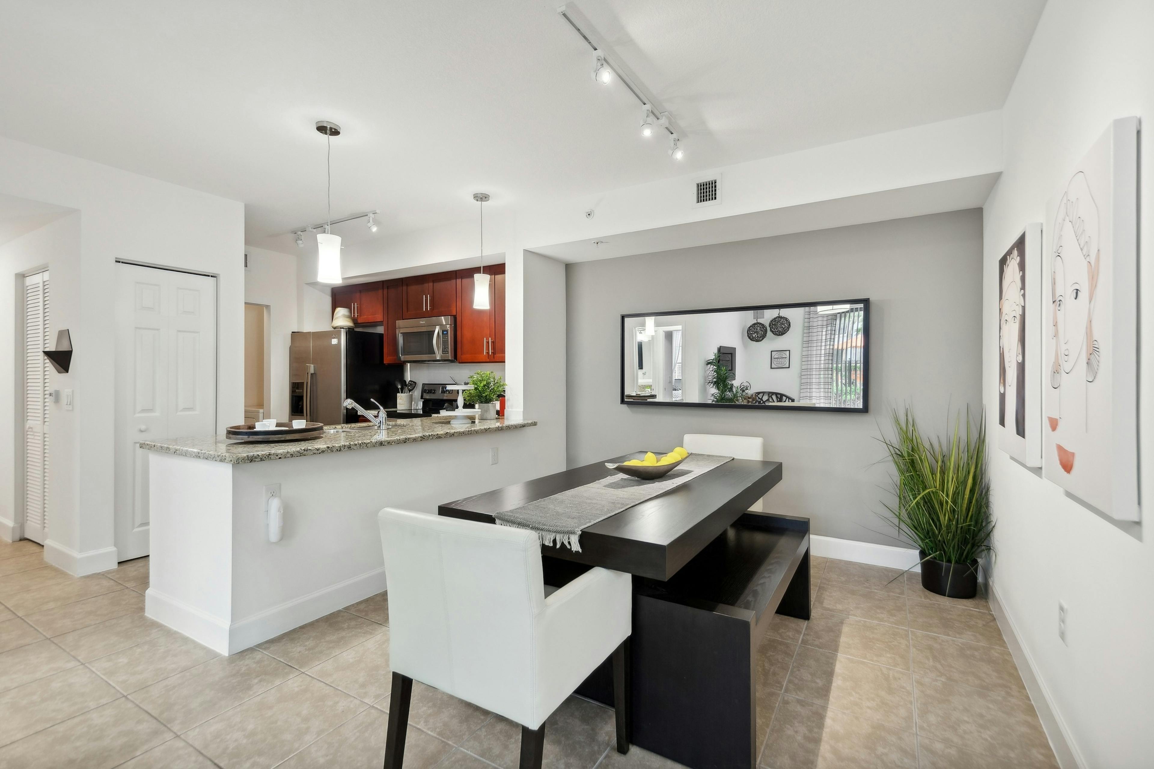 Dining room at AMLI Toscana Place apartments with a dining table looking into a kitchen with cherry cabinets and stainless steel appliances