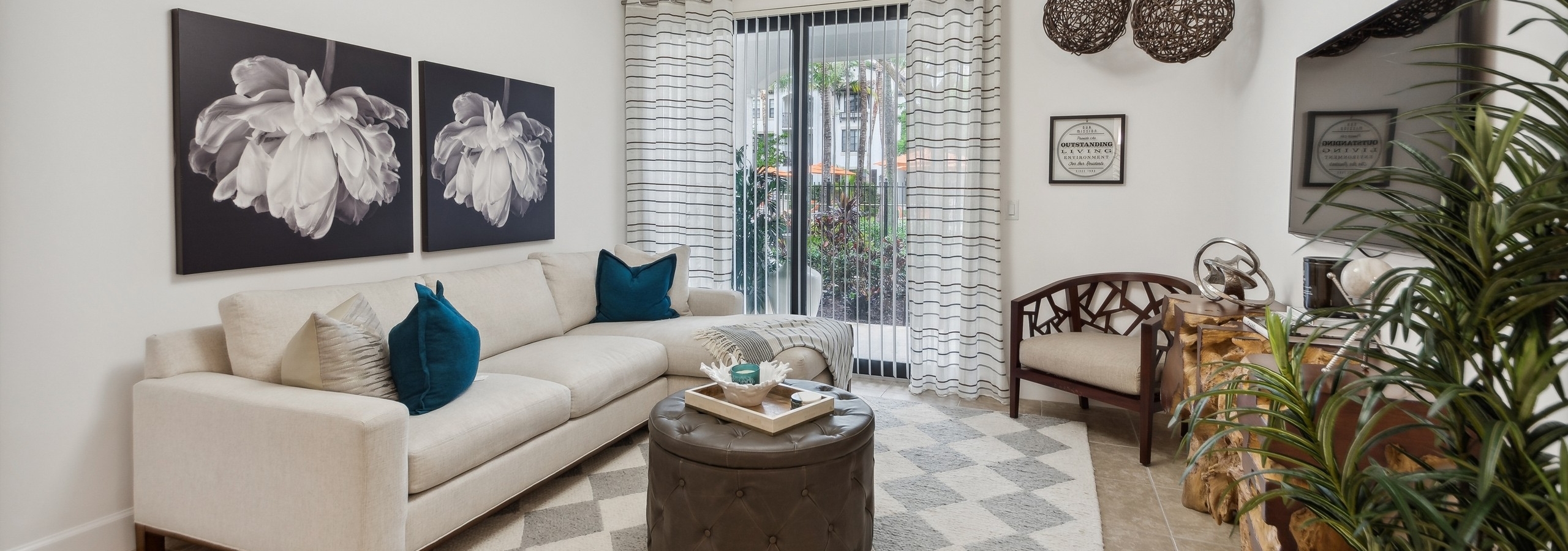 Living room at AMLI Toscana Place apartments with couch and coffee table overlooking a patio with sliding glass door and curtains