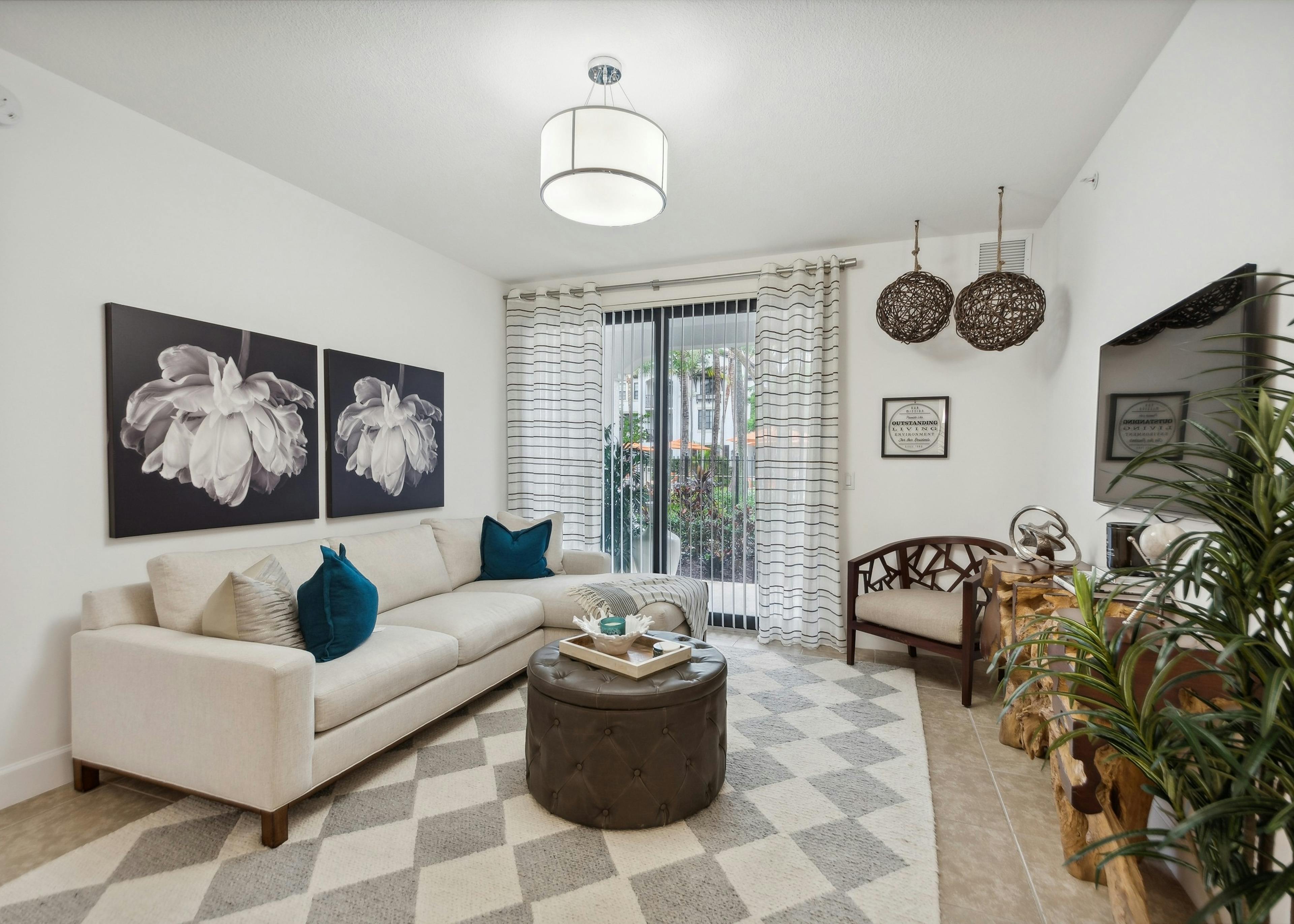 Living room at AMLI Toscana Place apartments with couch and coffee table overlooking a patio with sliding glass door and curtains