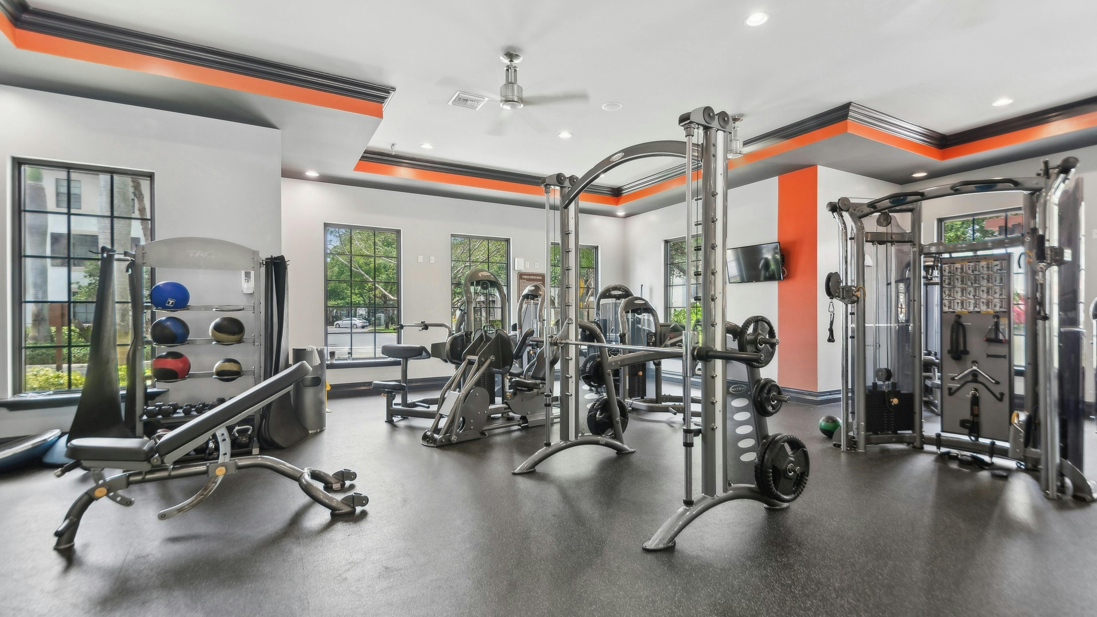 Interior of fitness center at AMLI Toscana Place with high endurance equipment and colorful walls and TVs and ceiling fans