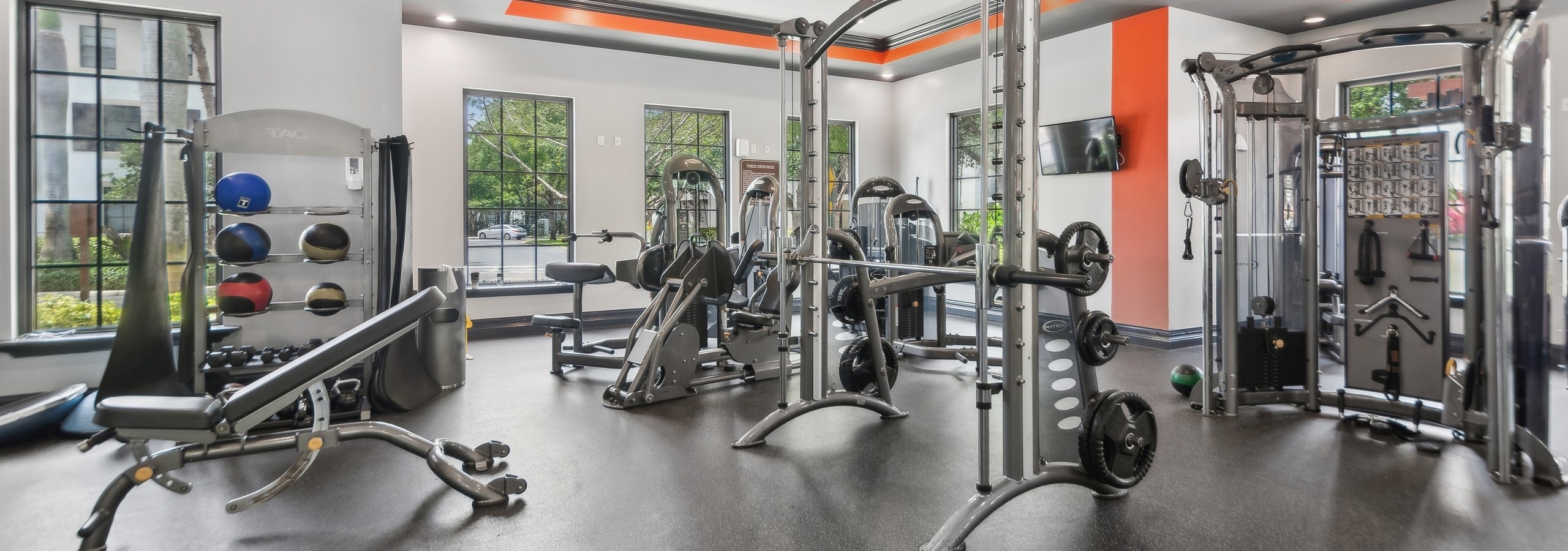 Interior of fitness center at AMLI Toscana Place with high endurance equipment and colorful walls and TVs and ceiling fans