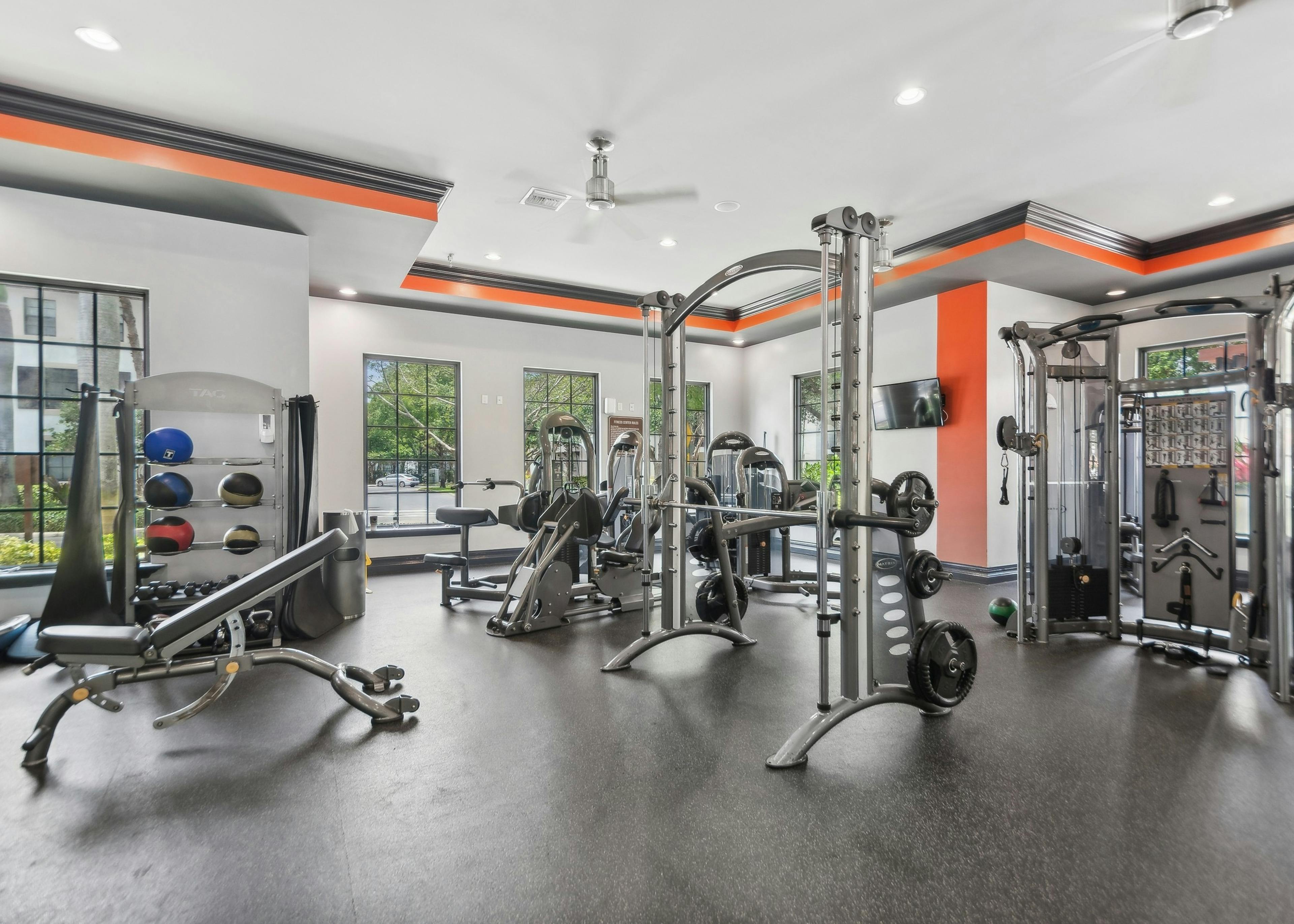 Interior of fitness center at AMLI Toscana Place with high endurance equipment and colorful walls and TVs and ceiling fans