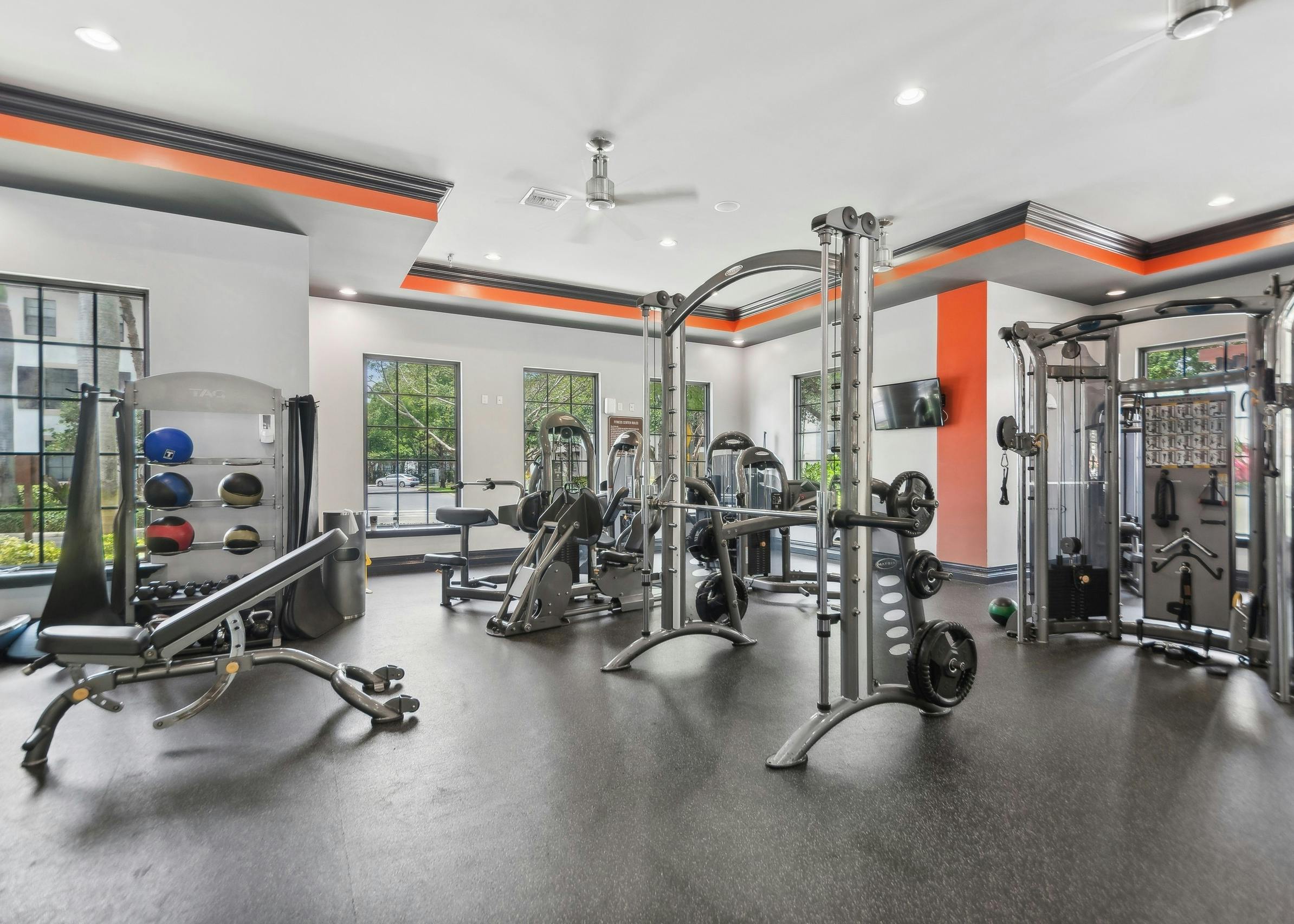 Interior of fitness center at AMLI Toscana Place with high endurance equipment and colorful walls and TVs and ceiling fans