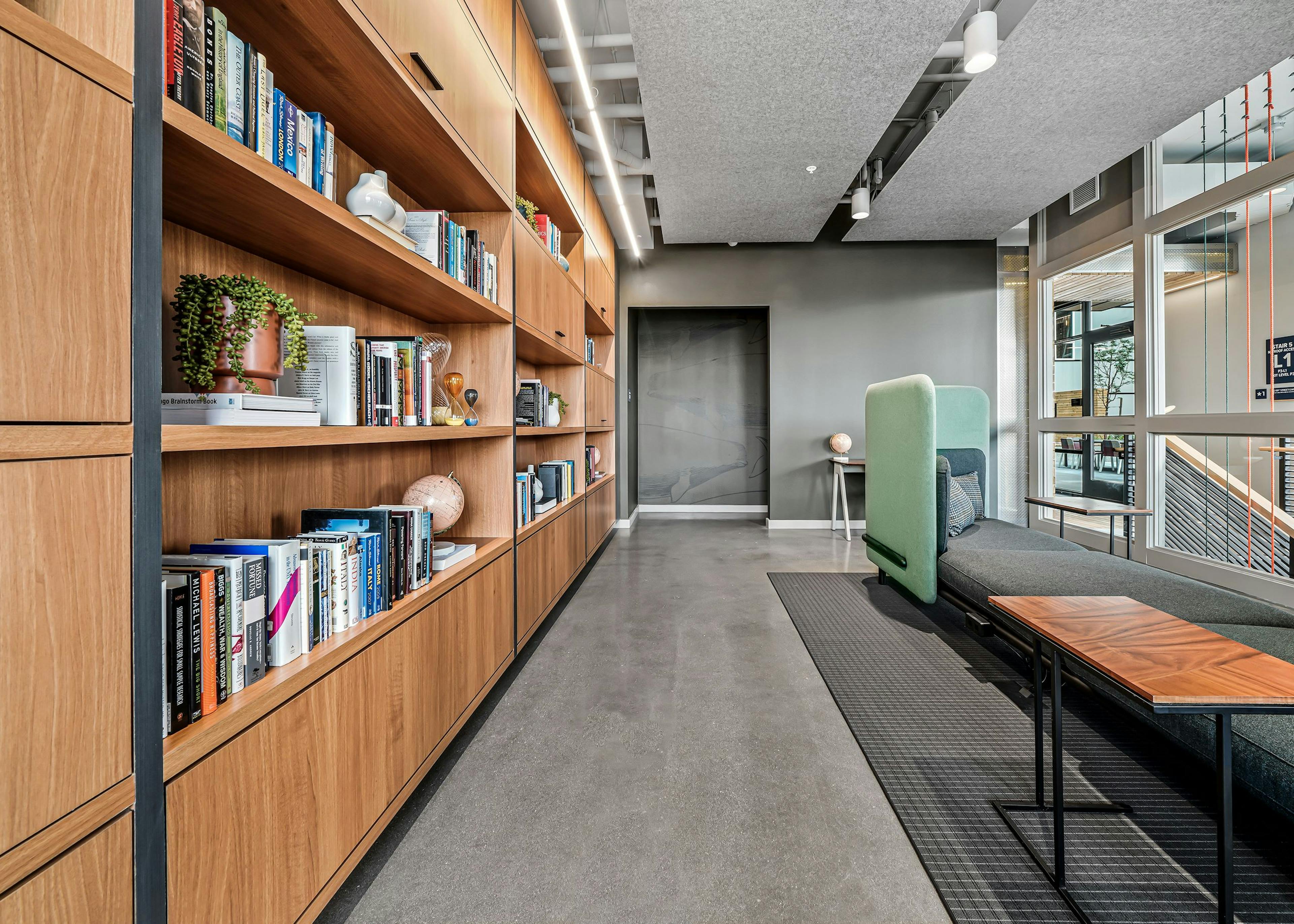 AMLI Spring District library with high ceilings and comfy booth and wood wall of shelves filled with books