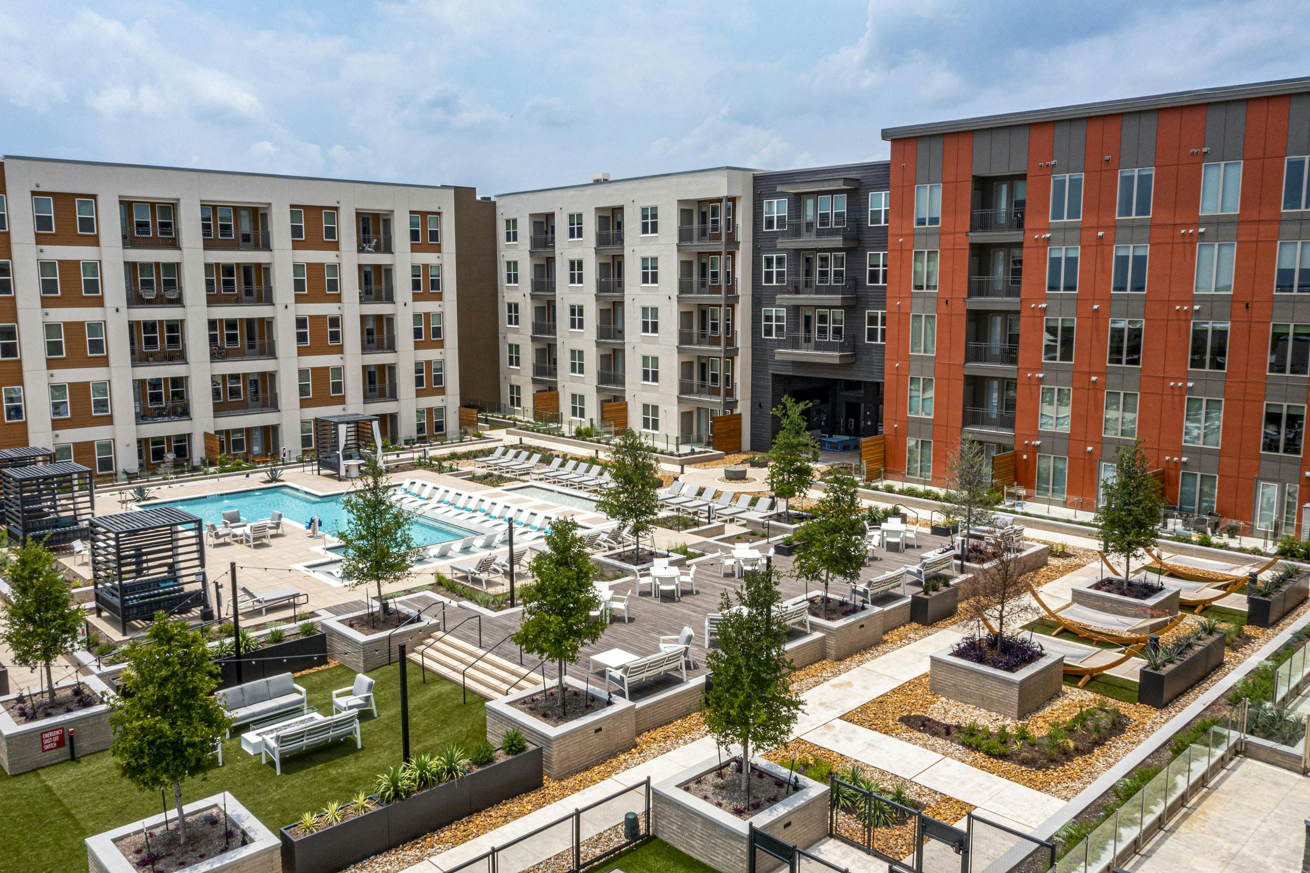 Aerial view of AMLI Branch Park apartments courtyard featuring a large pool, sun loungers, cabanas, tree planters and greenery
