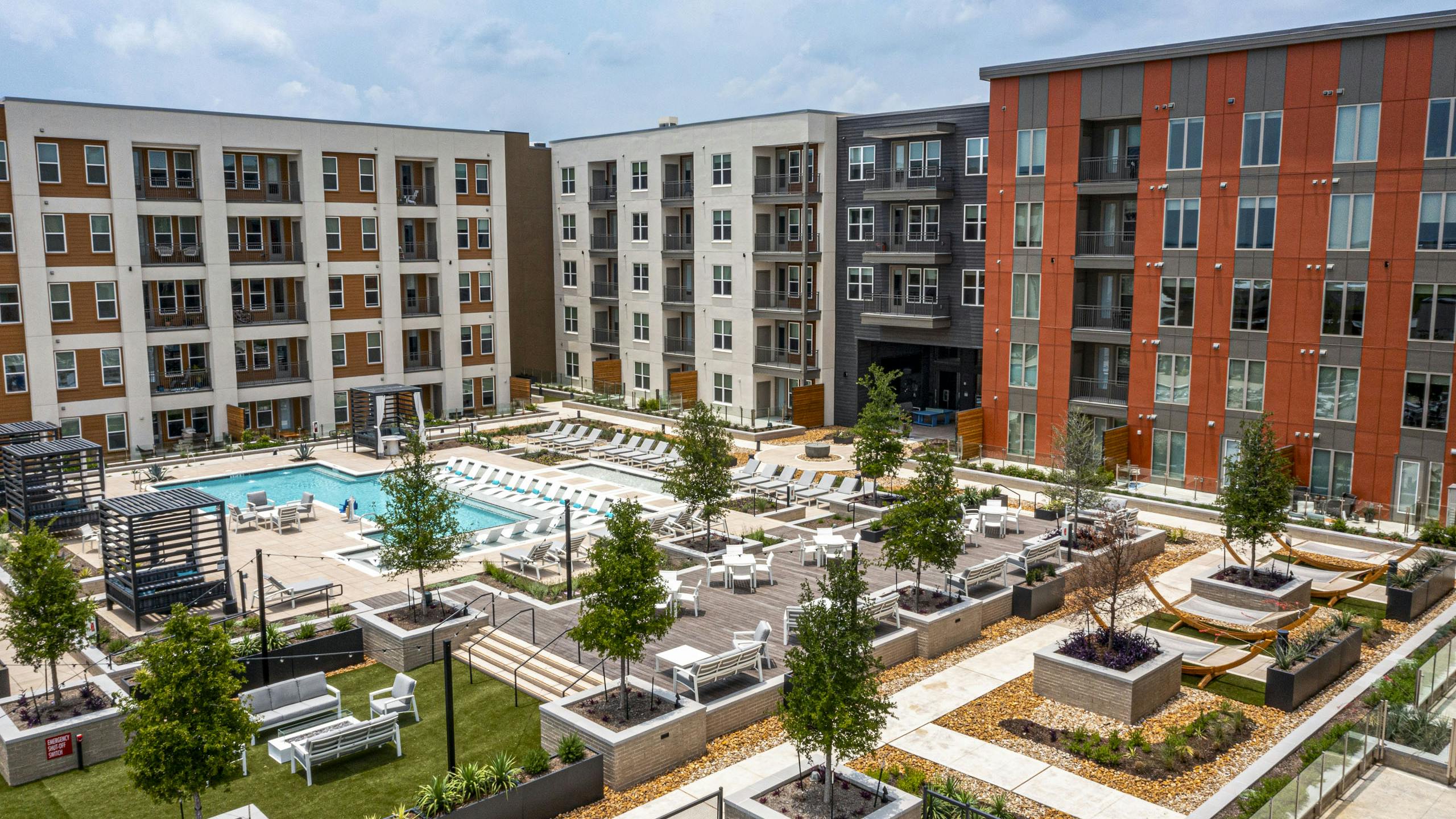 Aerial view of AMLI Branch Park apartments courtyard featuring a large pool, sun loungers, cabanas, tree planters and greenery
