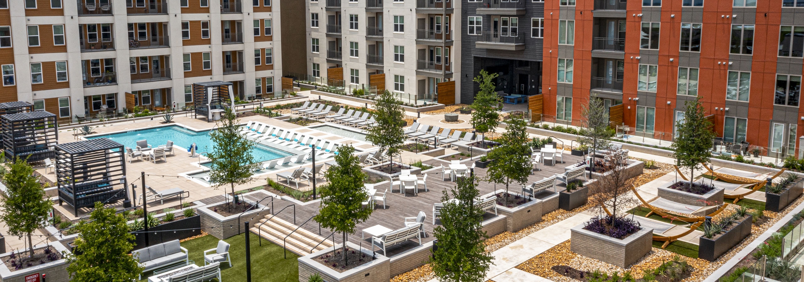 Aerial view of AMLI Branch Park apartments courtyard featuring a large pool, sun loungers, cabanas, tree planters and greenery