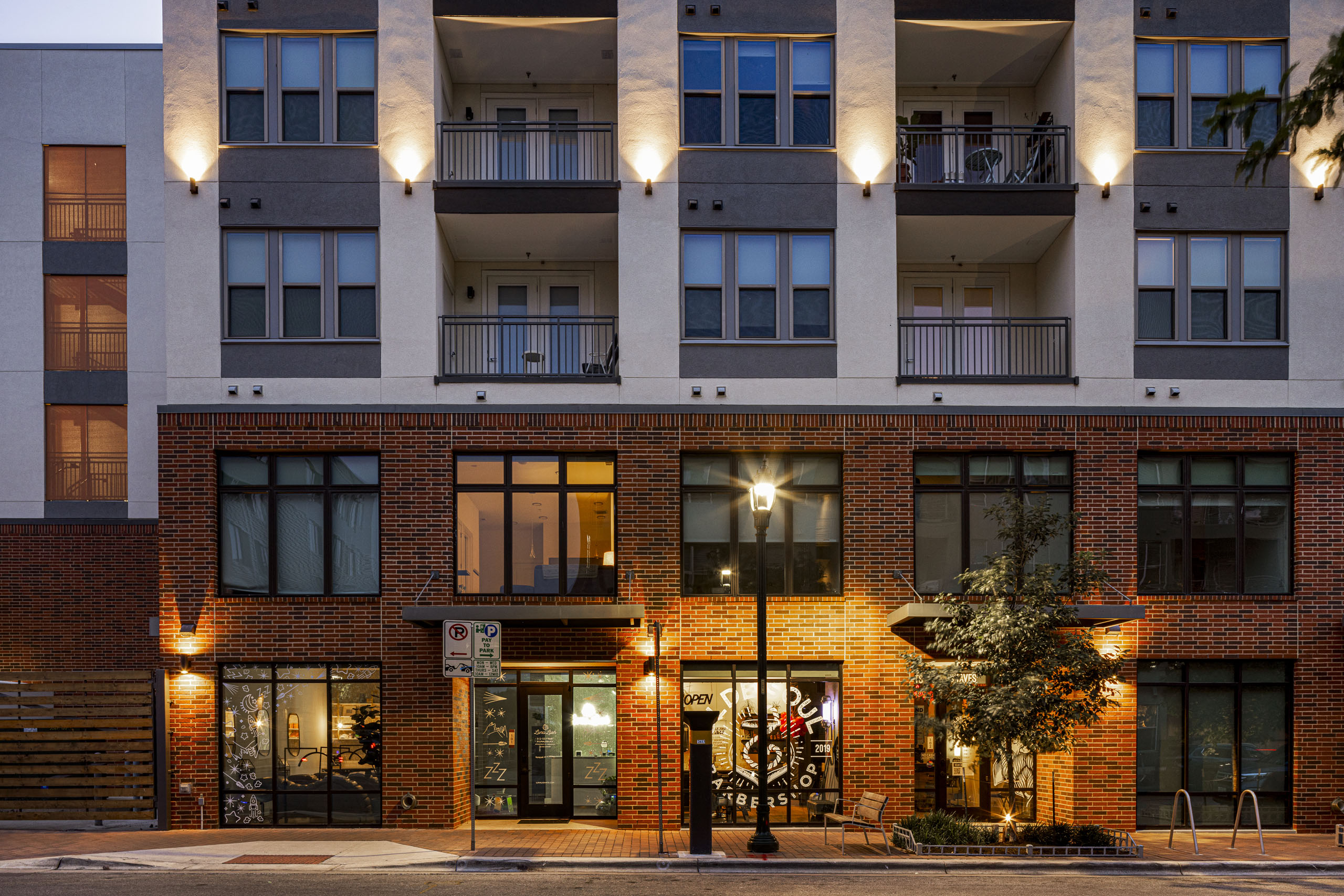 Evening view of AMLI Branch Park south apartment building exterior featuring red brick facade and large windows