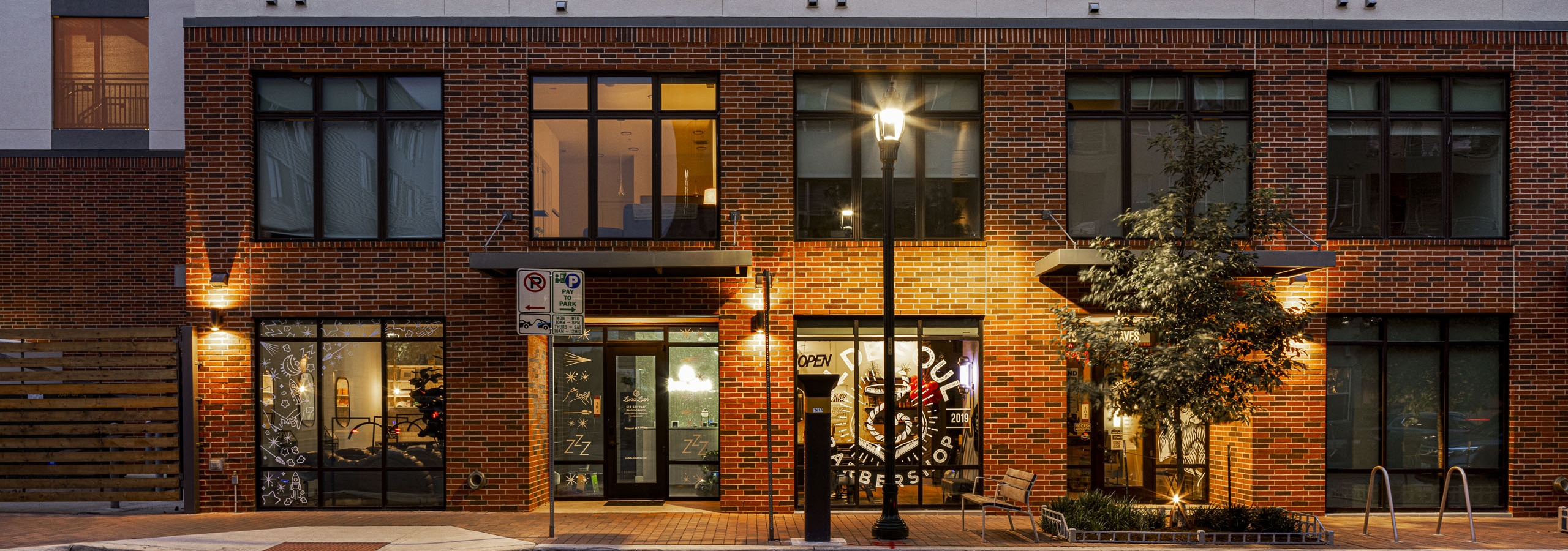 Evening view of AMLI Branch Park south apartment building exterior featuring red brick facade and large windows
