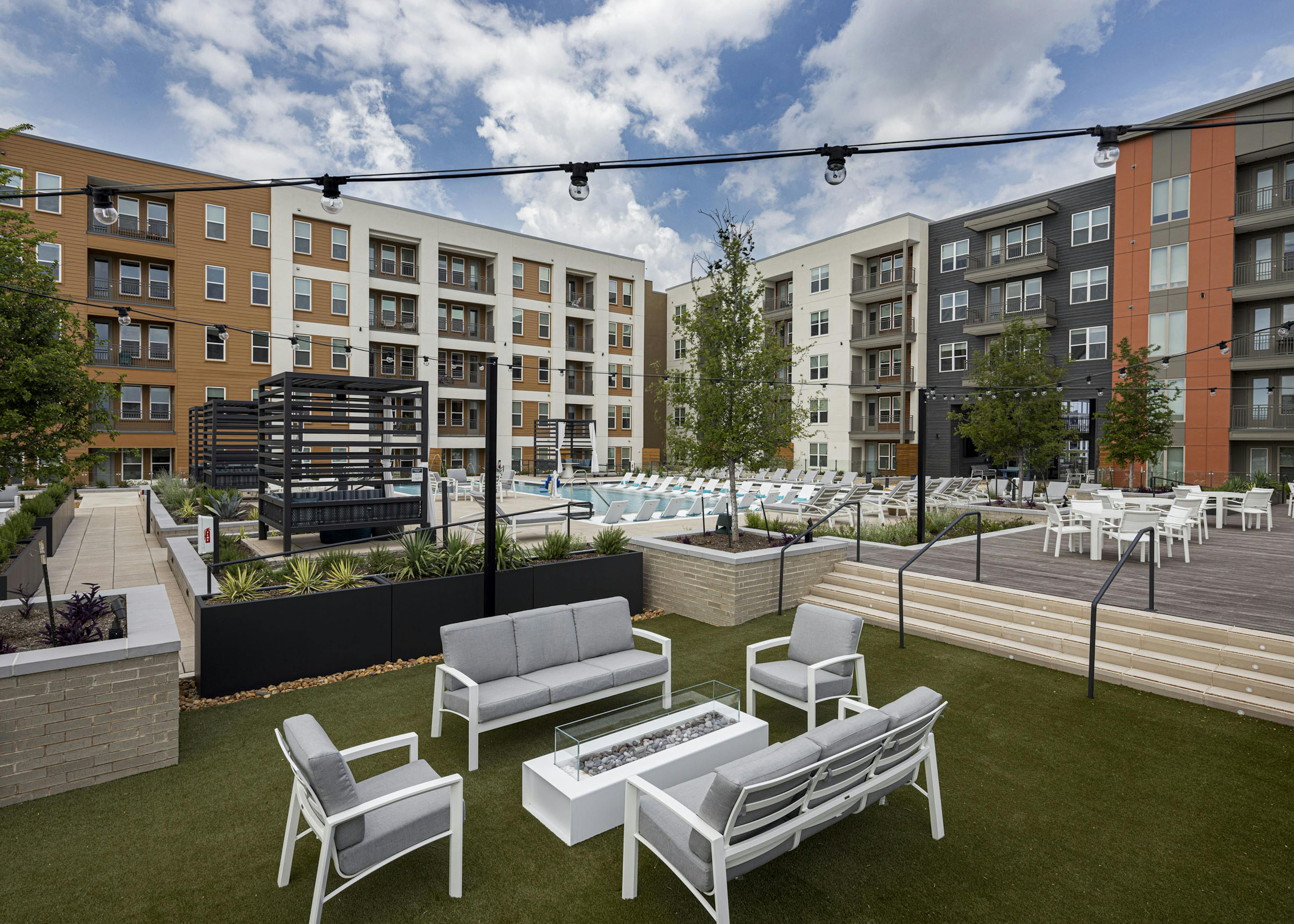 Resident courtyard at AMLI Branch Park featuring seating surrounding a firepit on turf and a pool in the background