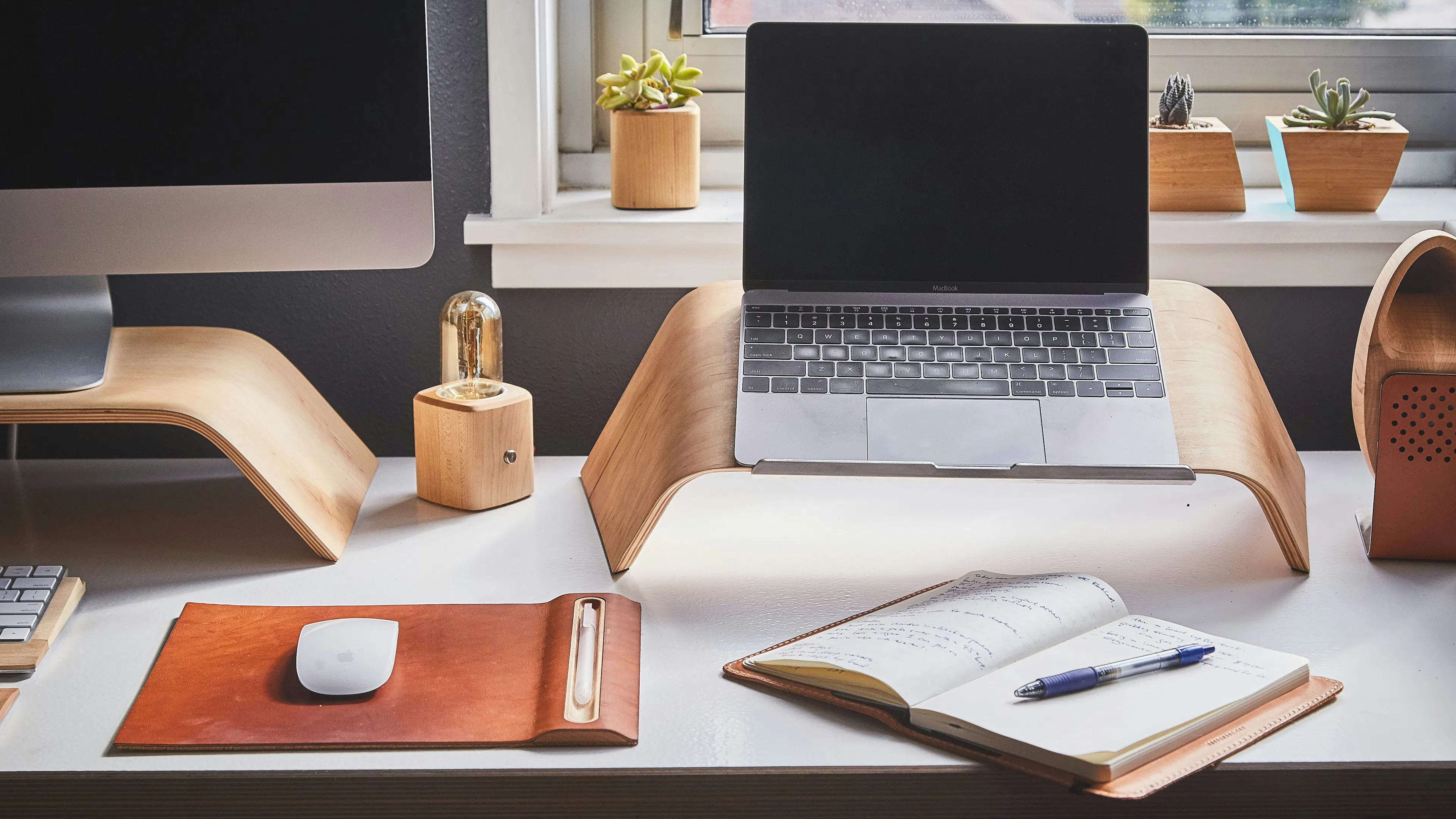 A sleek white home office desk with a laptop and a desktop computer alongside some office accessories