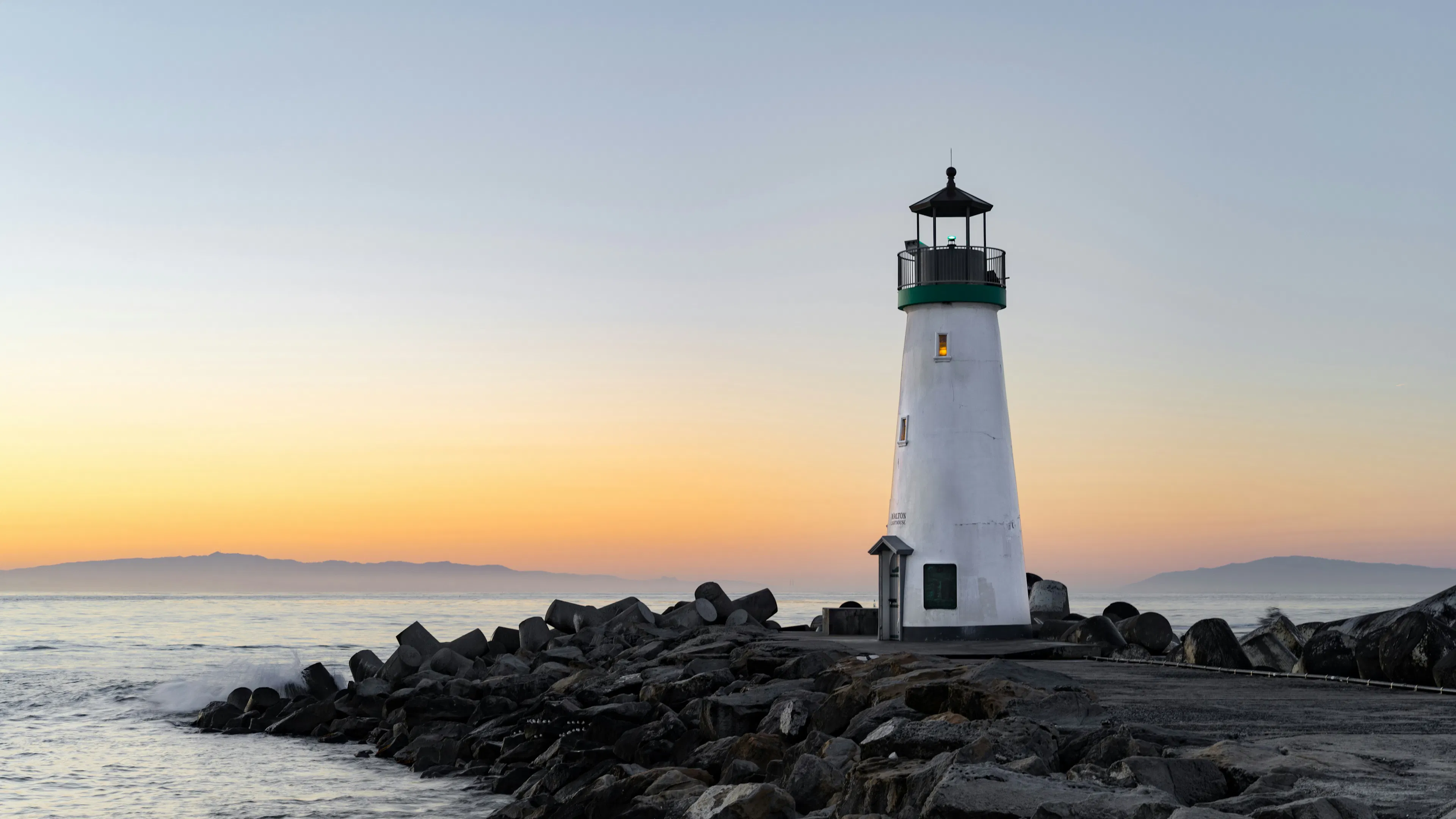 A white lighthouse at sunset on the coast