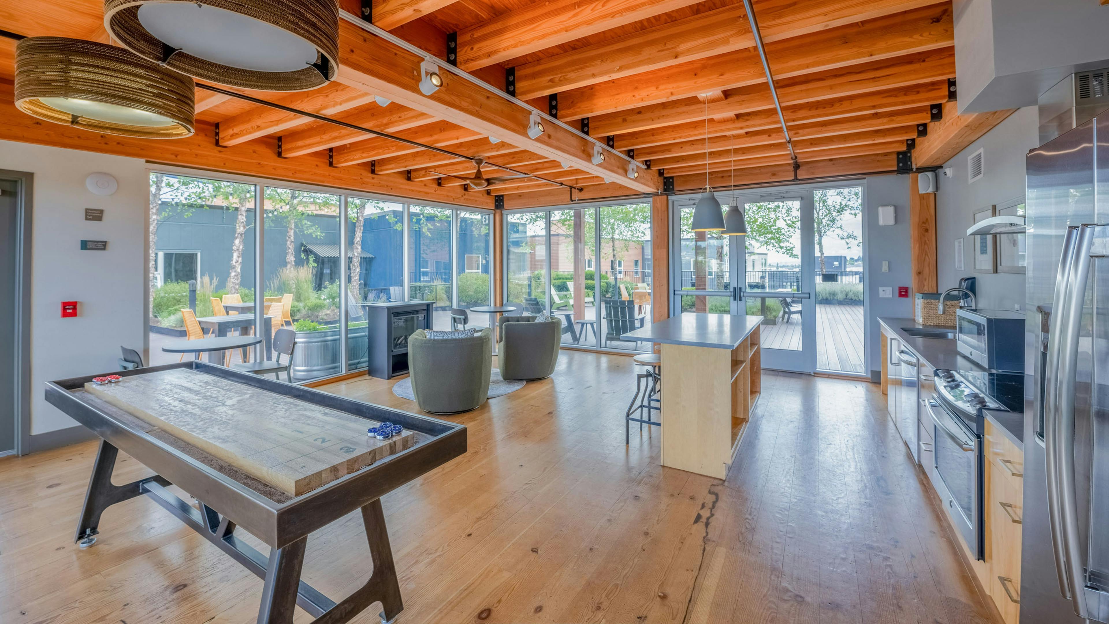 AMLI Mark24 sky lounge featuring kitchen with stainless appliances, an island with stools, a shuffleboard table, and view of rooftop patio