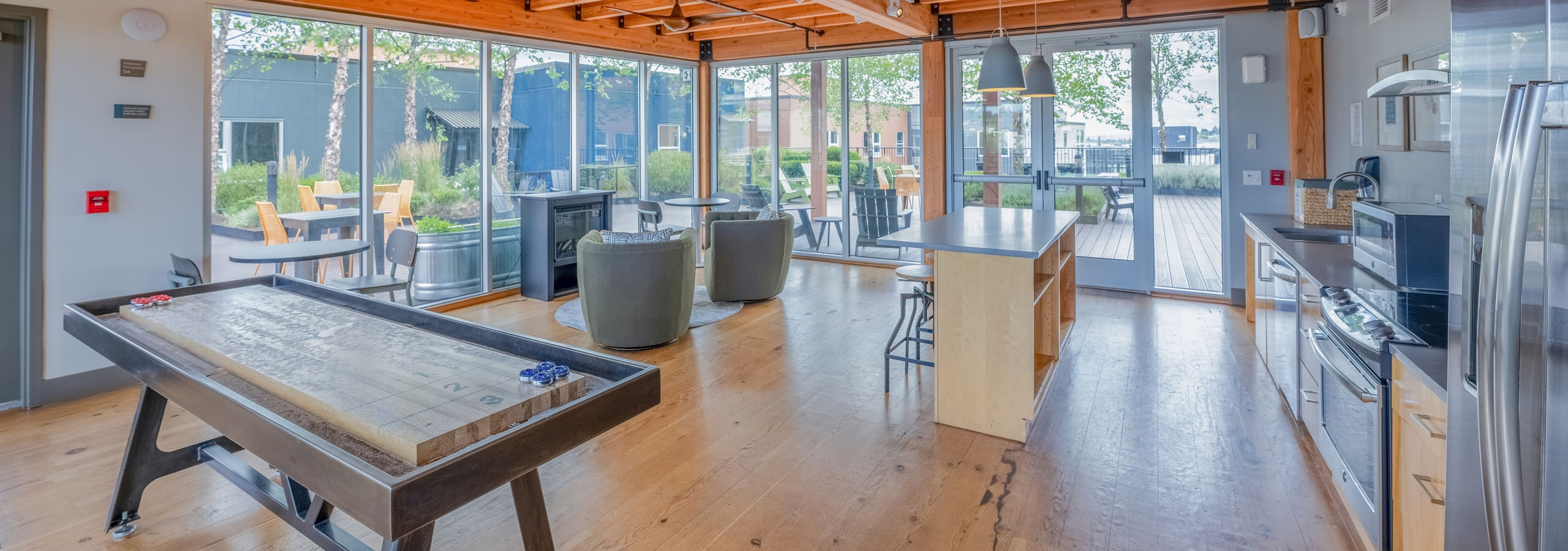 AMLI Mark24 sky lounge featuring kitchen with stainless appliances, an island with stools, a shuffleboard table, and view of rooftop patio