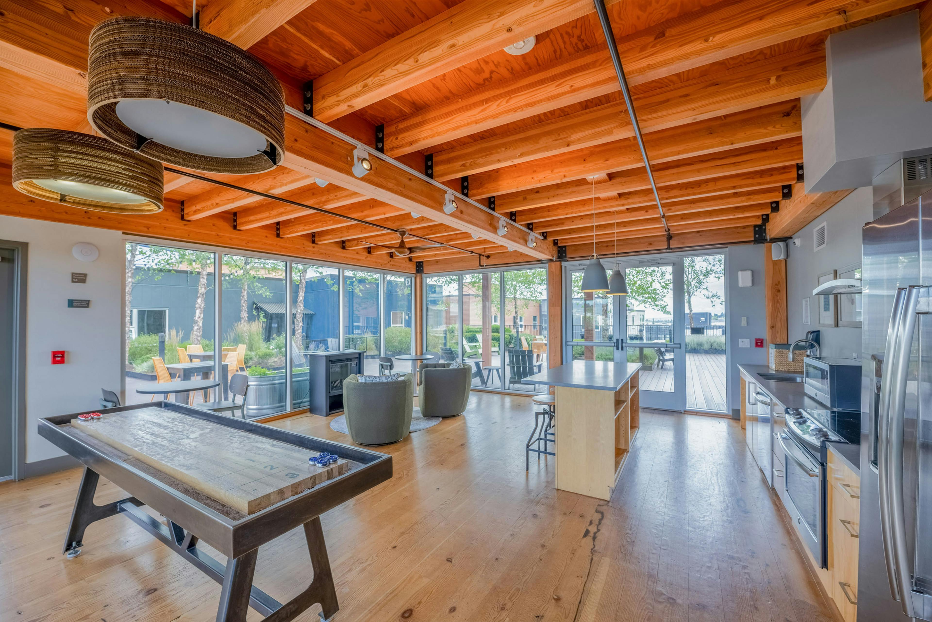 AMLI Mark24 sky lounge featuring kitchen with stainless appliances, an island with stools, a shuffleboard table, and view of rooftop patio