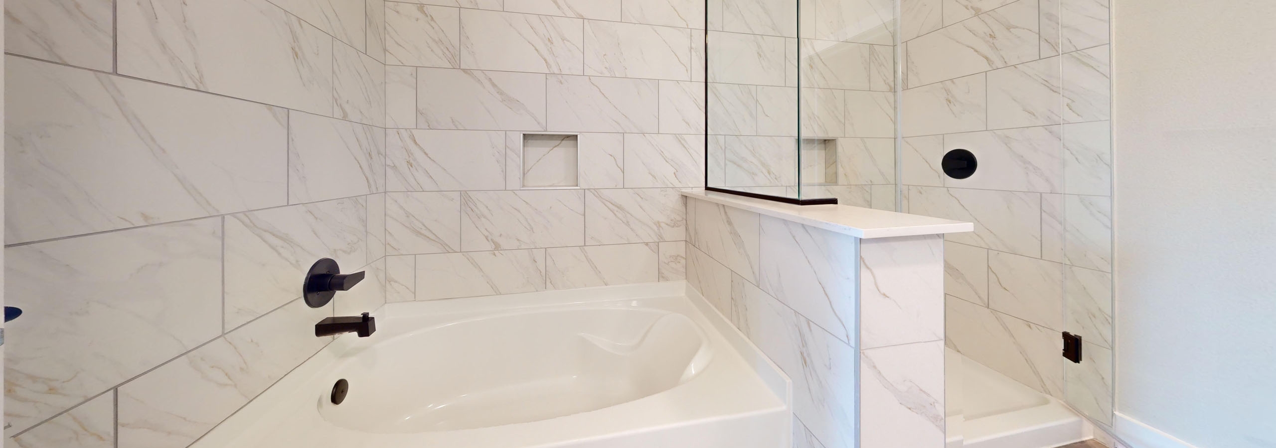 Contemporary bathroom with a walk-in shower and a white garden tub with tile surround throughout at AMLI North Park apartments