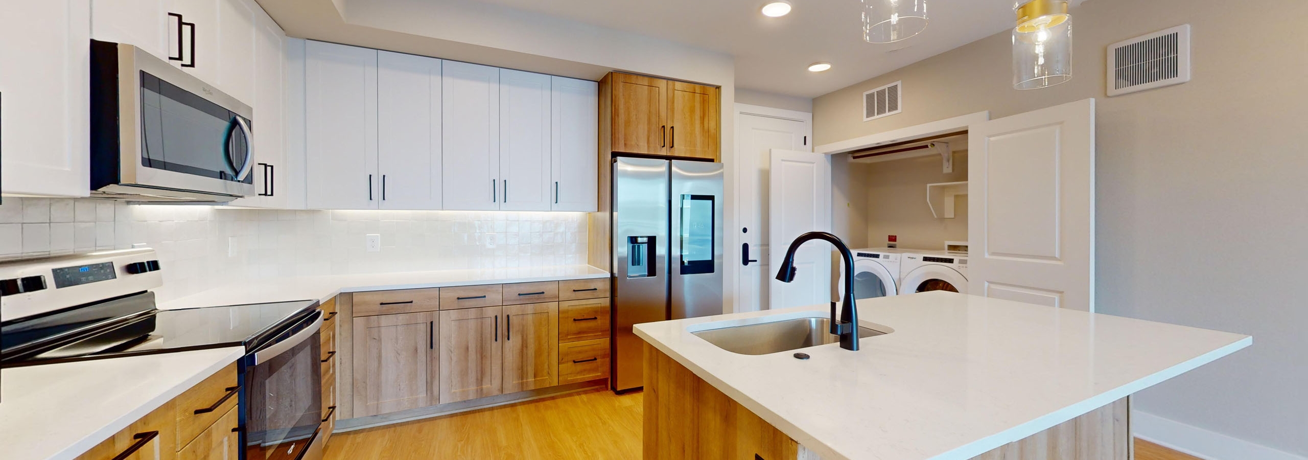 AMLI North Park island kitchen with white upper and wood lower cabinetry, white quartz countertops and tile backsplash and wood floors