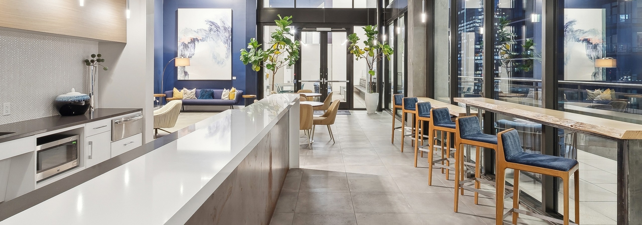 Skydeck kitchen area at AMLI Arts Center with thin long counters across from each other with blue cushioned barstools facing windows