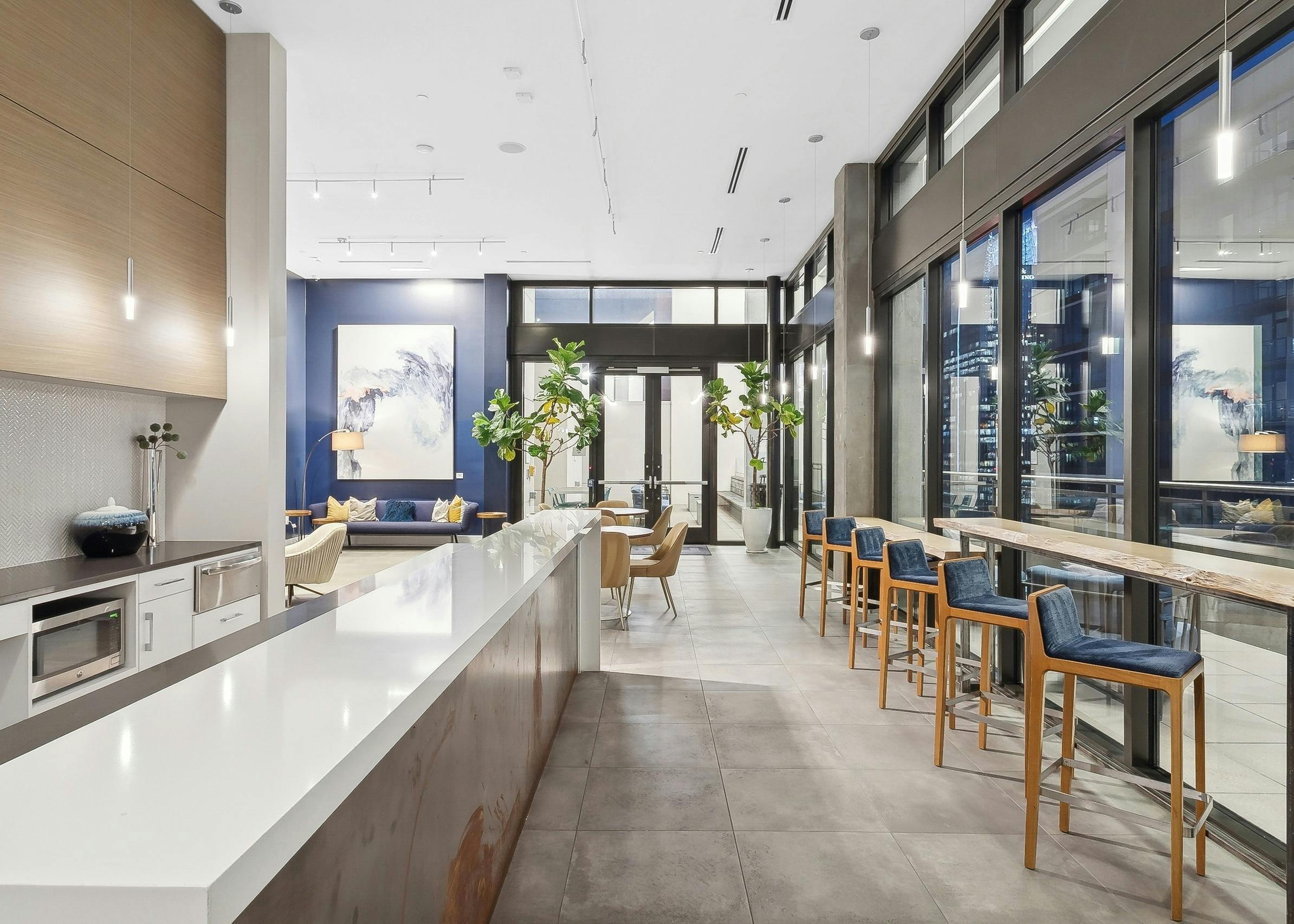 Skydeck kitchen area at AMLI Arts Center with thin long counters across from each other with blue cushioned barstools facing windows
