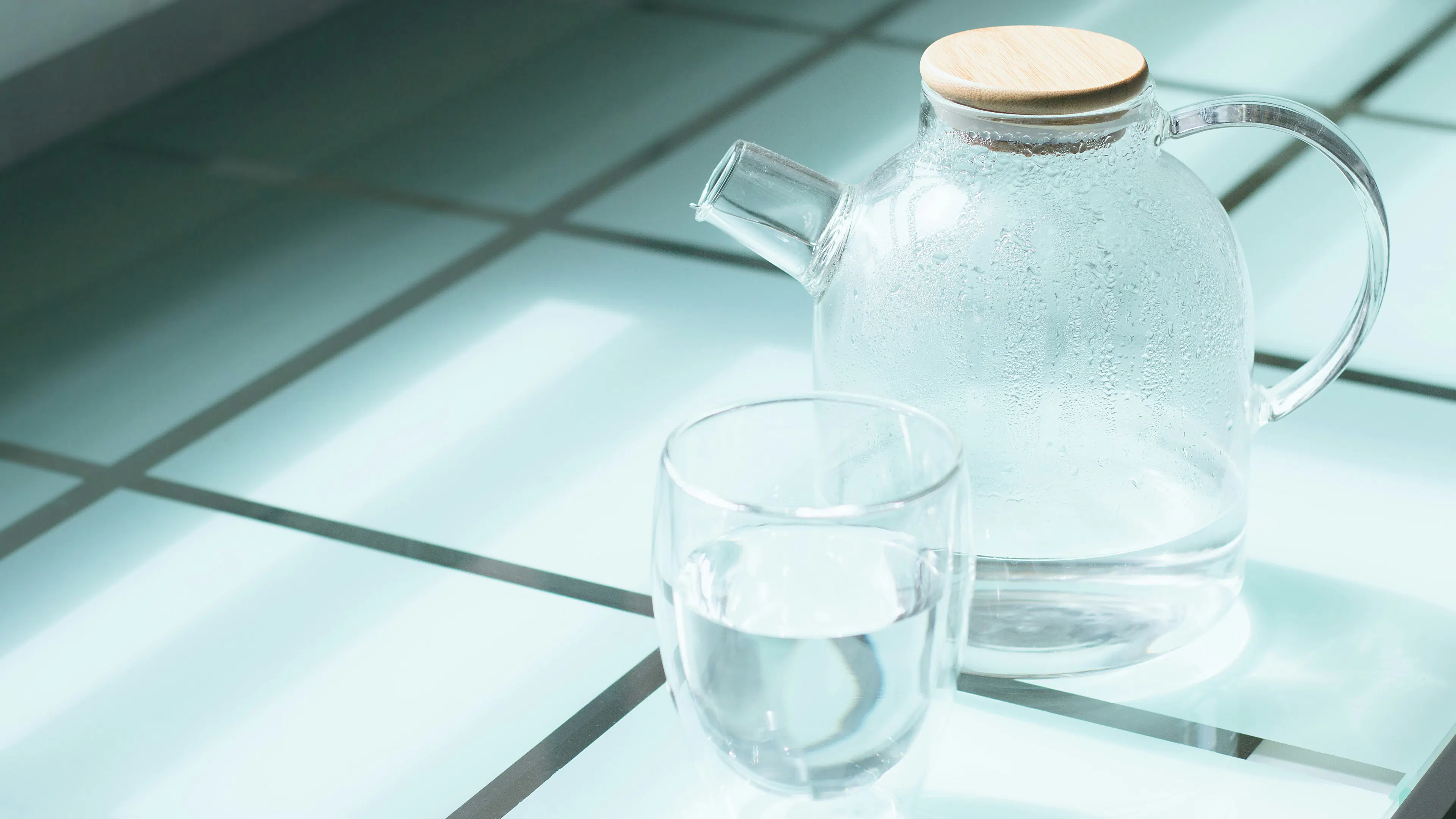 A clear glass jug of water and a glass cup filled with clean water 