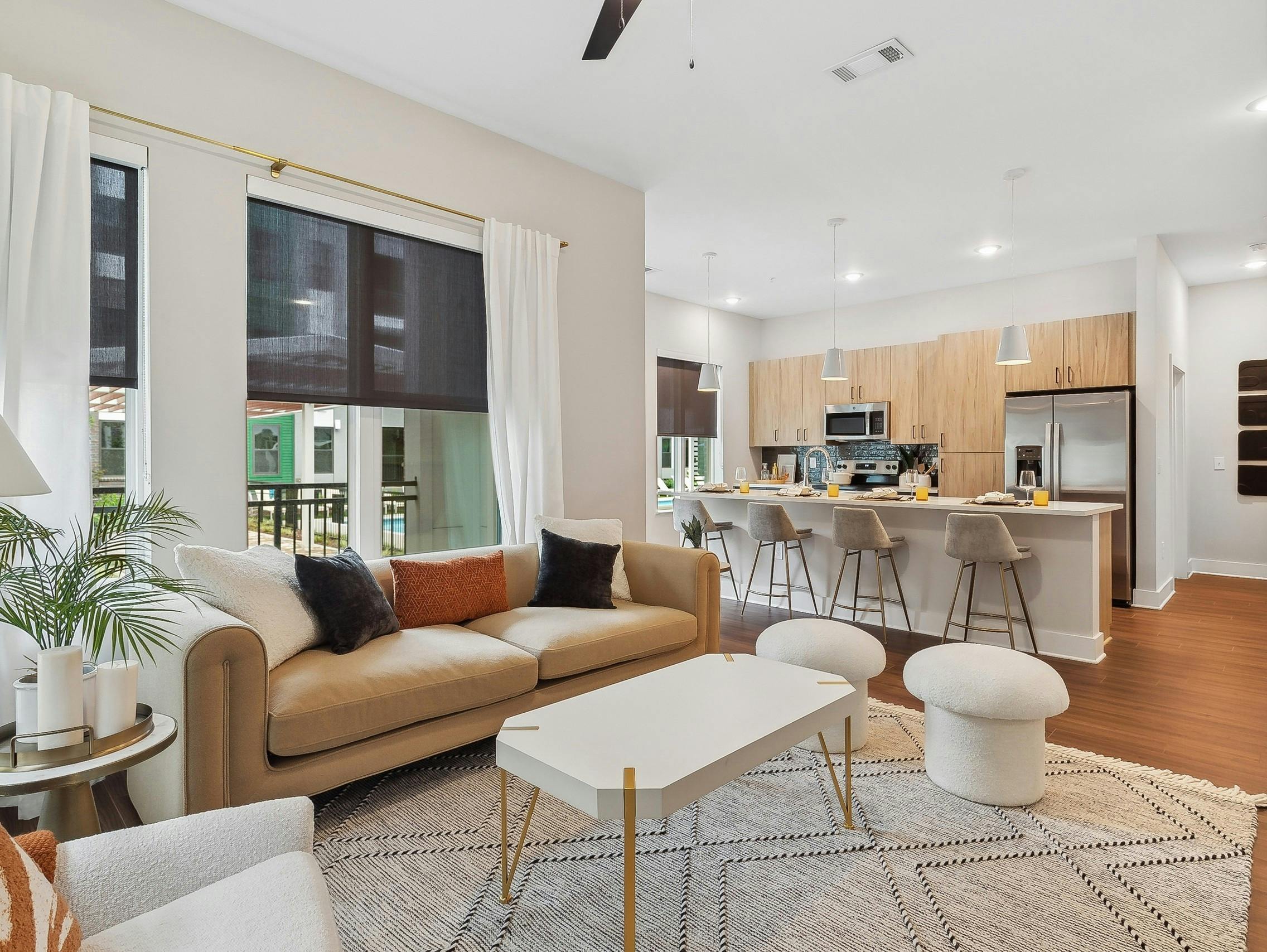 AMLI Flatiron living room with a beige sofa with orange and black pillows and a white coffee table with view of kitchen in rear