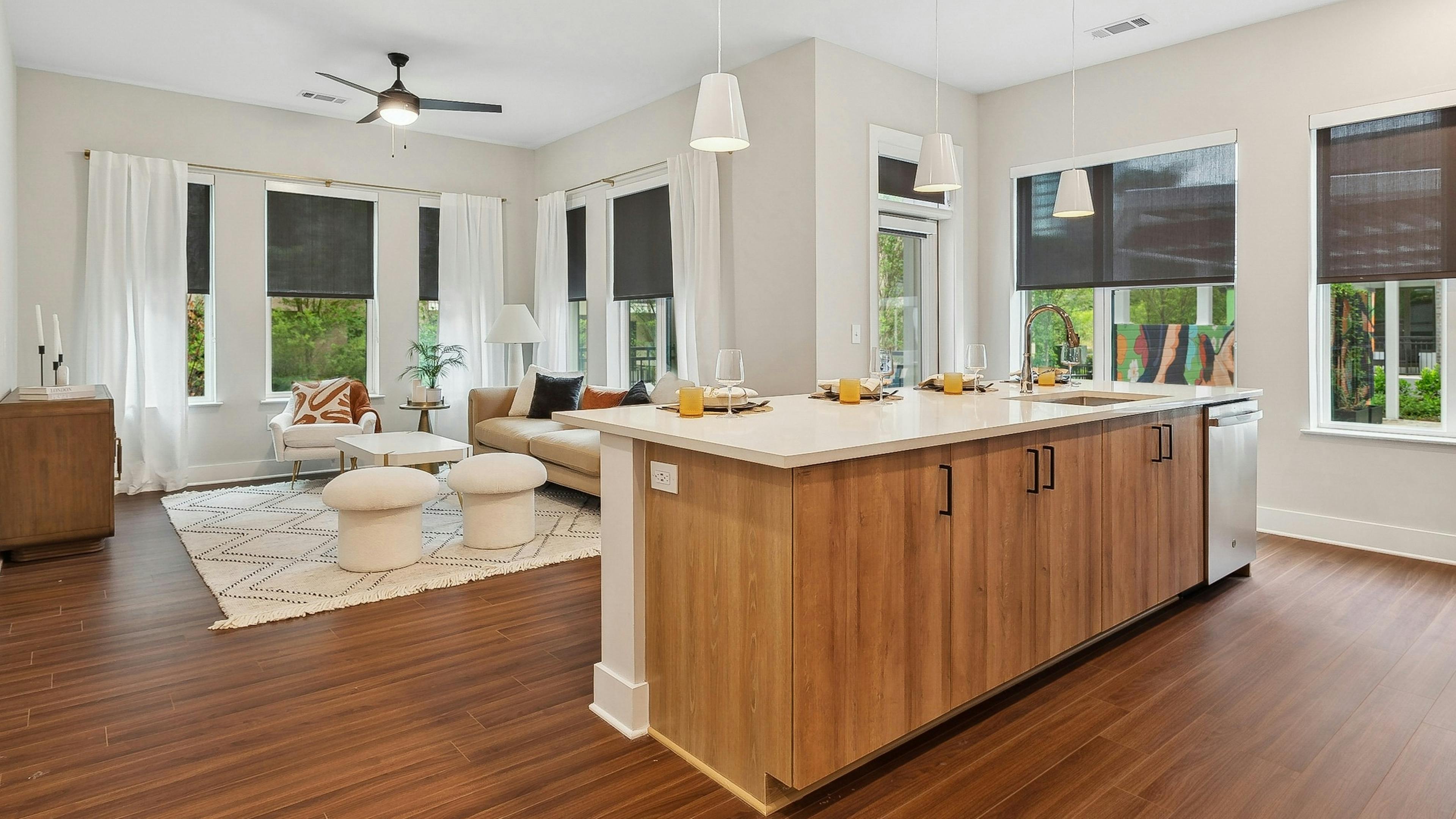 A kitchen island overlooking an open concept living room with wood floors at AMLI Flatiron with a with a sectional sofa and coffee table