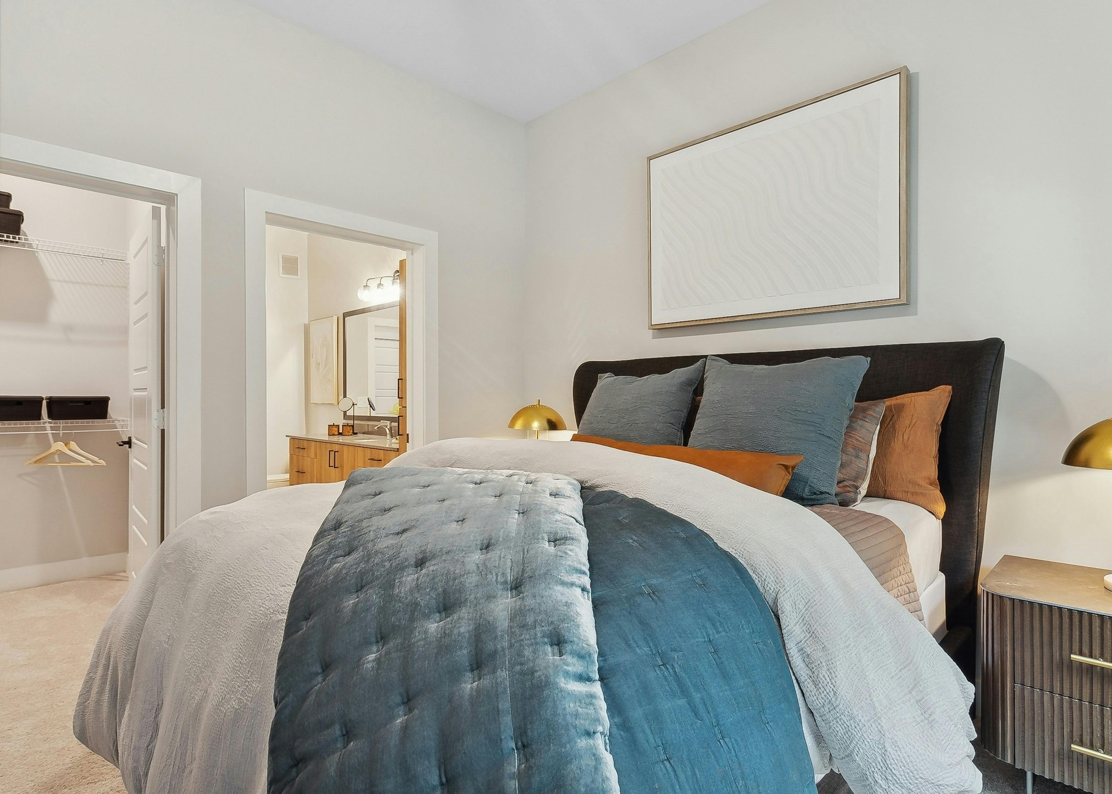 AMLI Flatiron bedroom with a neatly made bed featuring blue and white bedding with matching nightstands with gold lamps