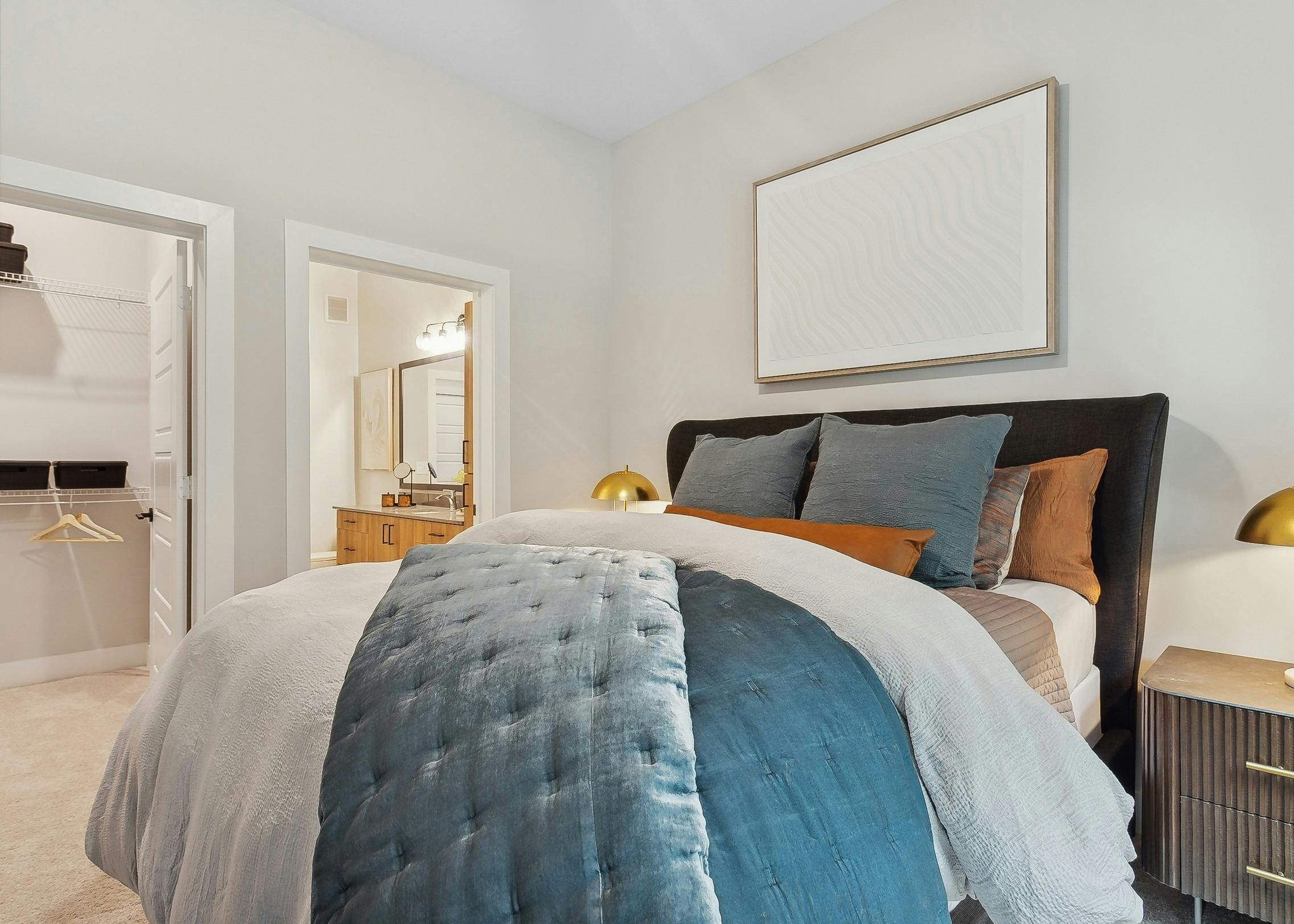 AMLI Flatiron bedroom with a neatly made bed featuring blue and white bedding with matching nightstands with gold lamps