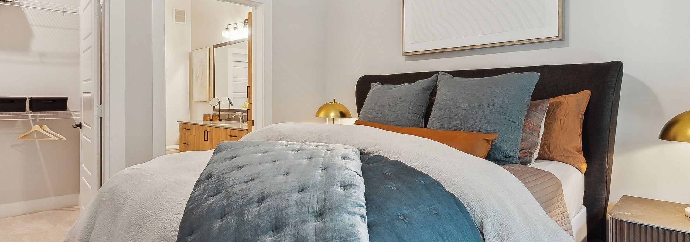AMLI Flatiron bedroom with a neatly made bed featuring blue and white bedding with matching nightstands with gold lamps