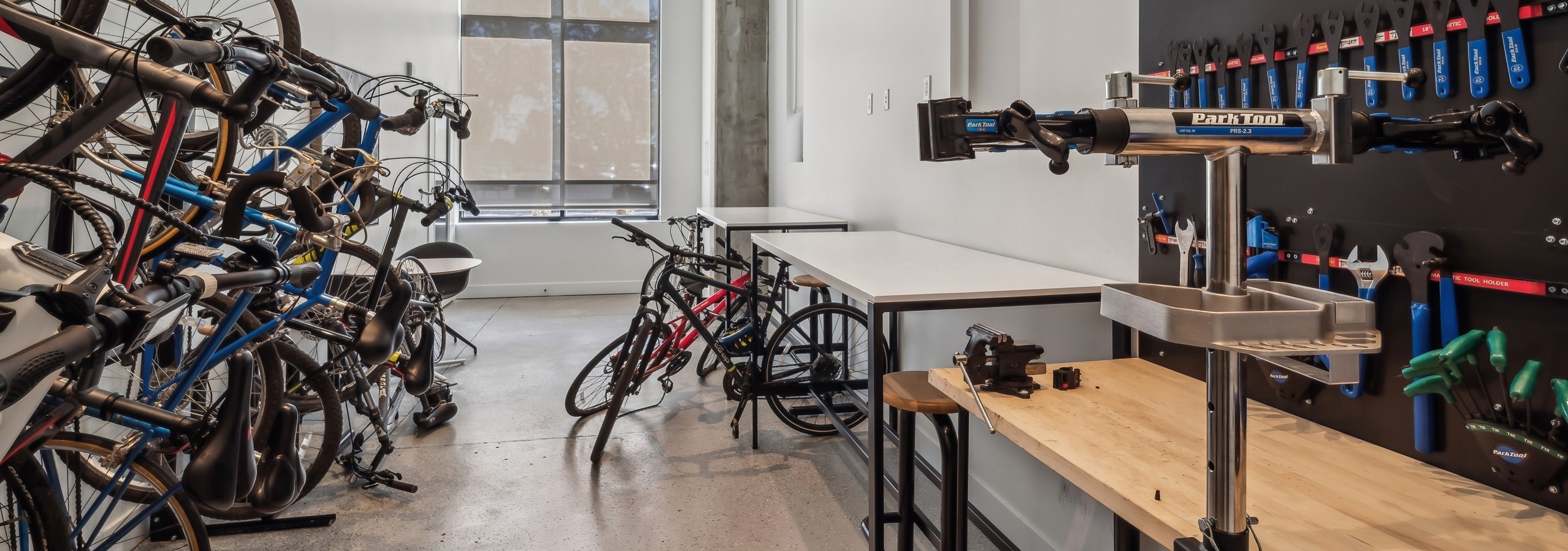Bike repair workshop at AMLI Broadway Park apartments featuring multiple bikes mounted on a rack and a workbench with various tools is on the opposite side