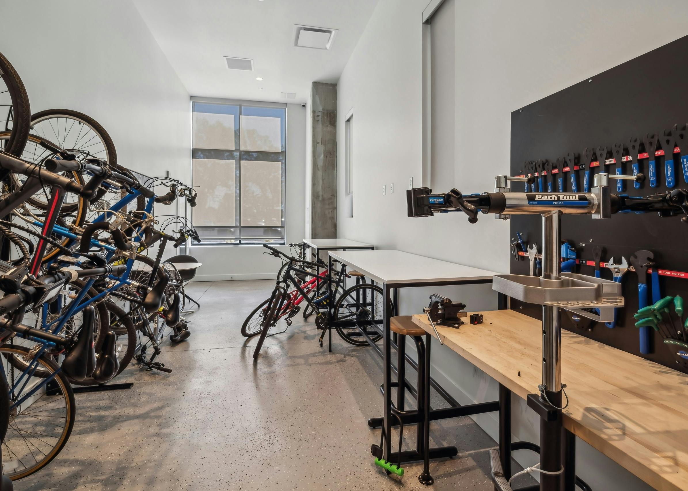 Bike repair workshop at AMLI Broadway Park apartments featuring multiple bikes mounted on a rack and a workbench with various tools is on the opposite side
