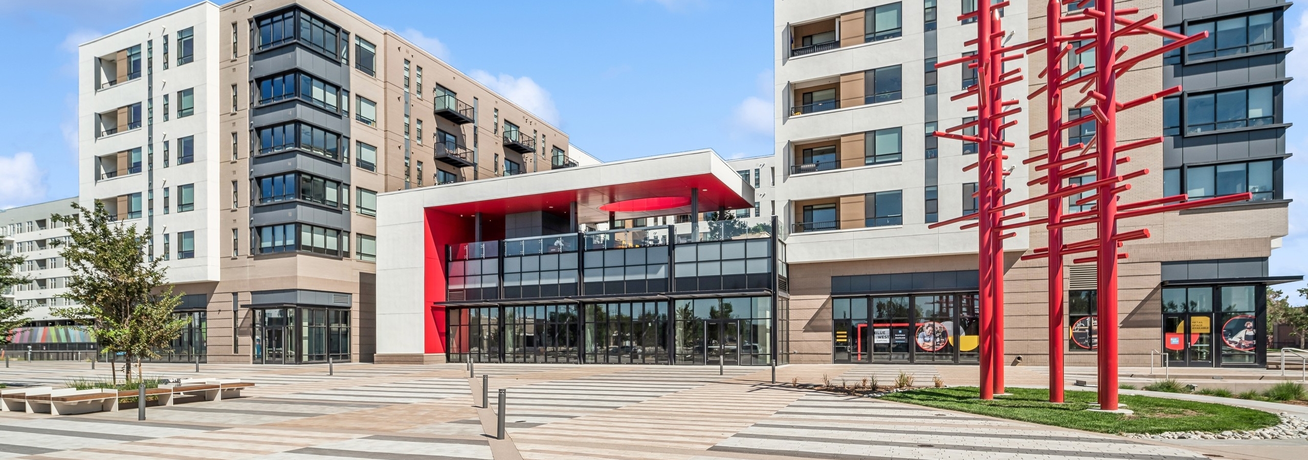 The modern white and tan AMLI Broadway Park apartment building with red architectural accents and red metal sculpture at Byers Square