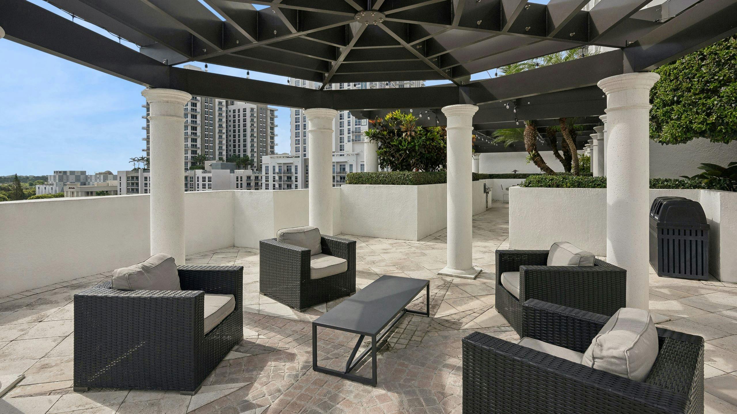Rooftop lounge at AMLI Joya with a geometric brown pergola above four brown wicker armchairs with tan cushions and brown coffee table