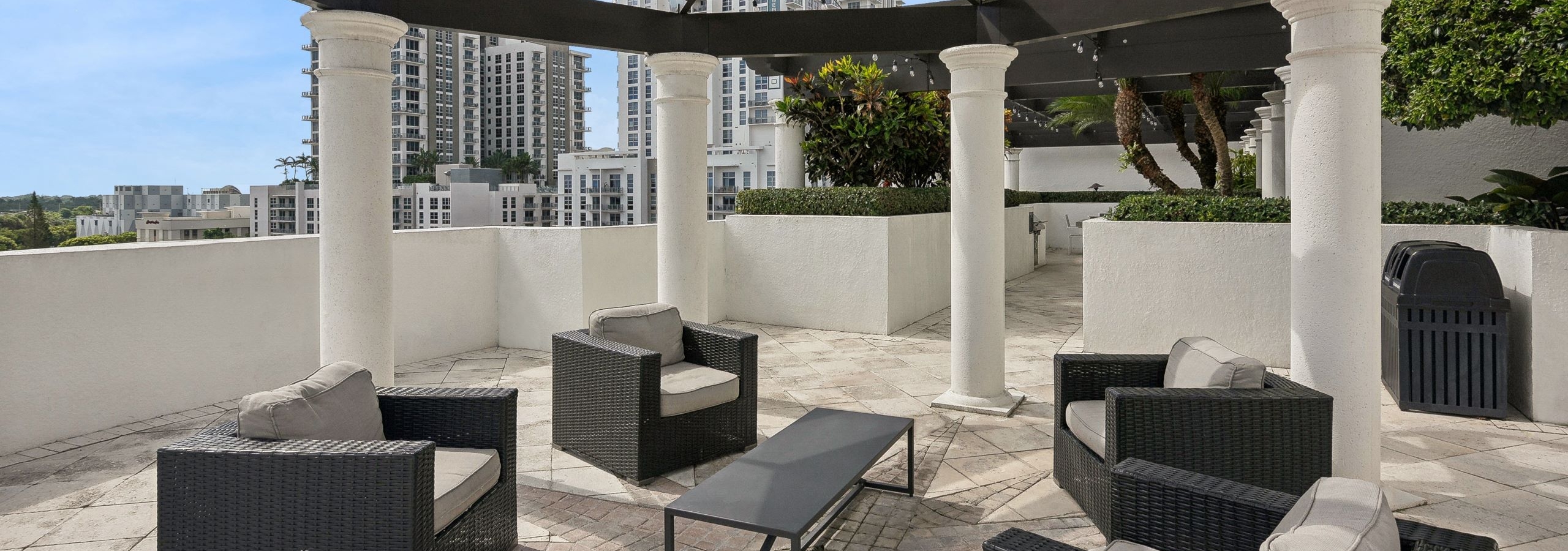 Rooftop lounge at AMLI Joya with a geometric brown pergola above four brown wicker armchairs with tan cushions and brown coffee table