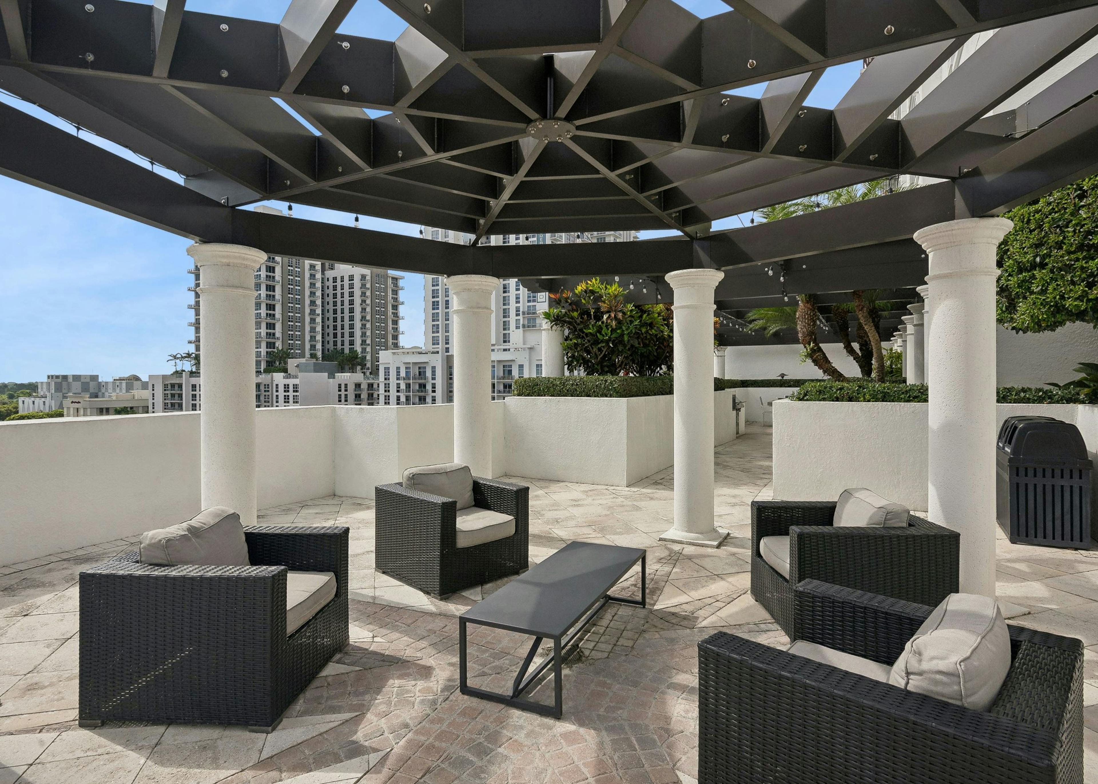 Rooftop lounge at AMLI Joya with a geometric brown pergola above four brown wicker armchairs with tan cushions and brown coffee table