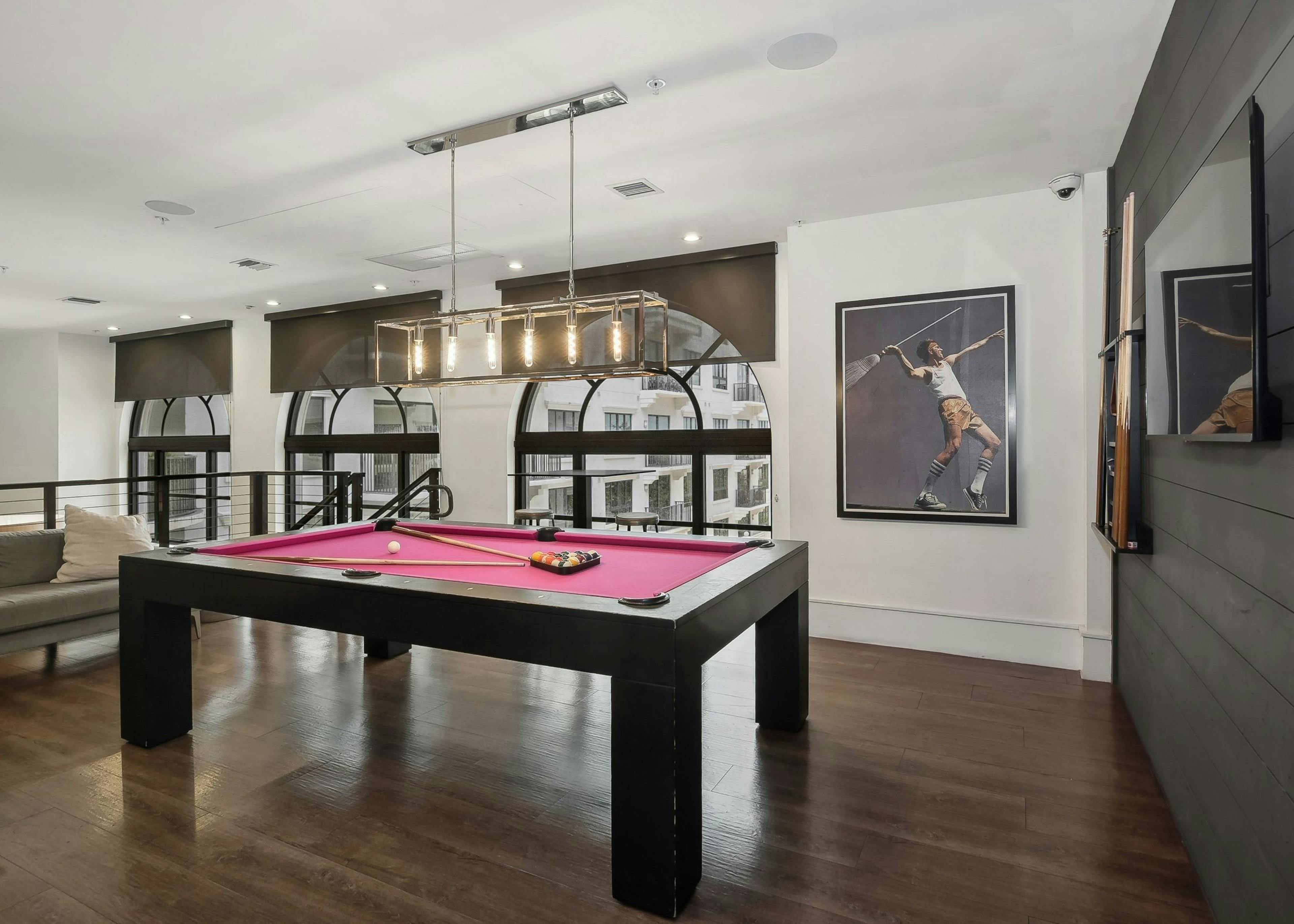 Second floor interior view of the AMLI Joya two story game room with red felt  billiards table and artwork of tennis player 
