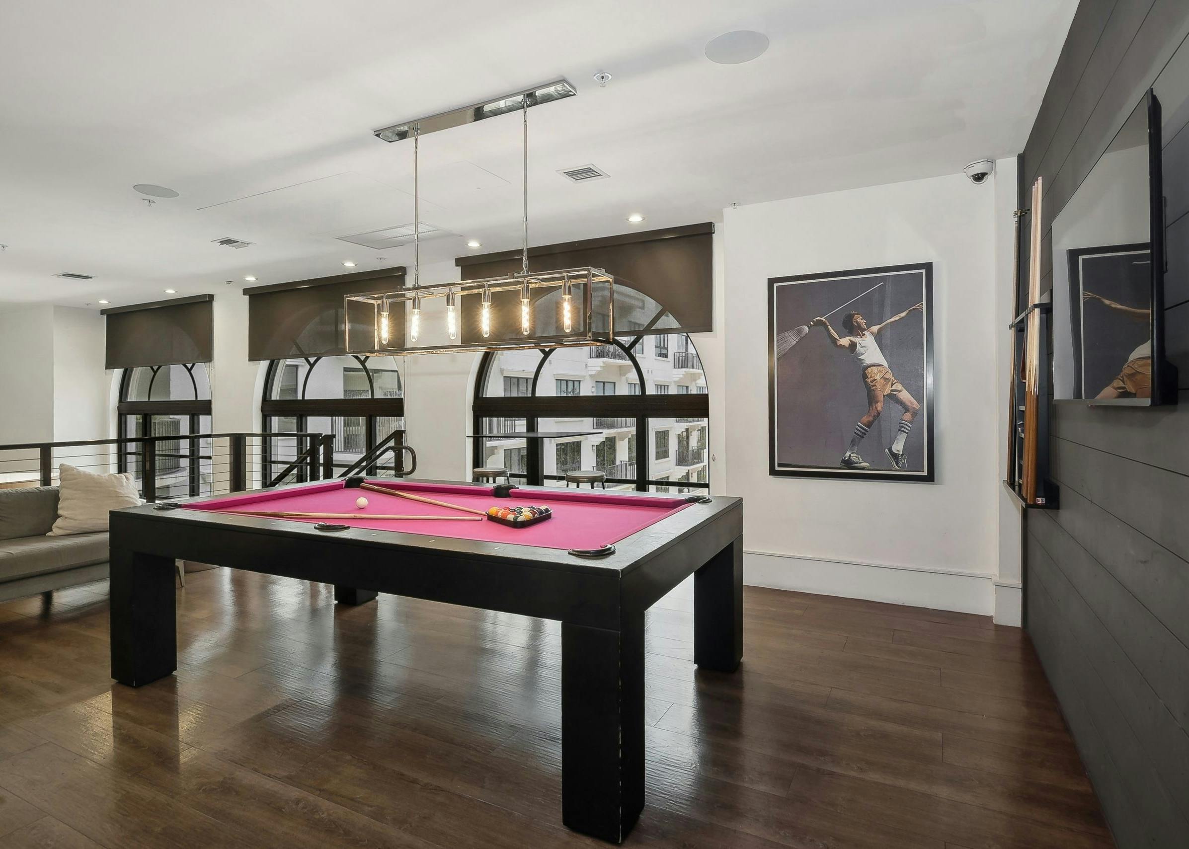 Second floor interior view of the AMLI Joya two story game room with red felt  billiards table and artwork of tennis player
