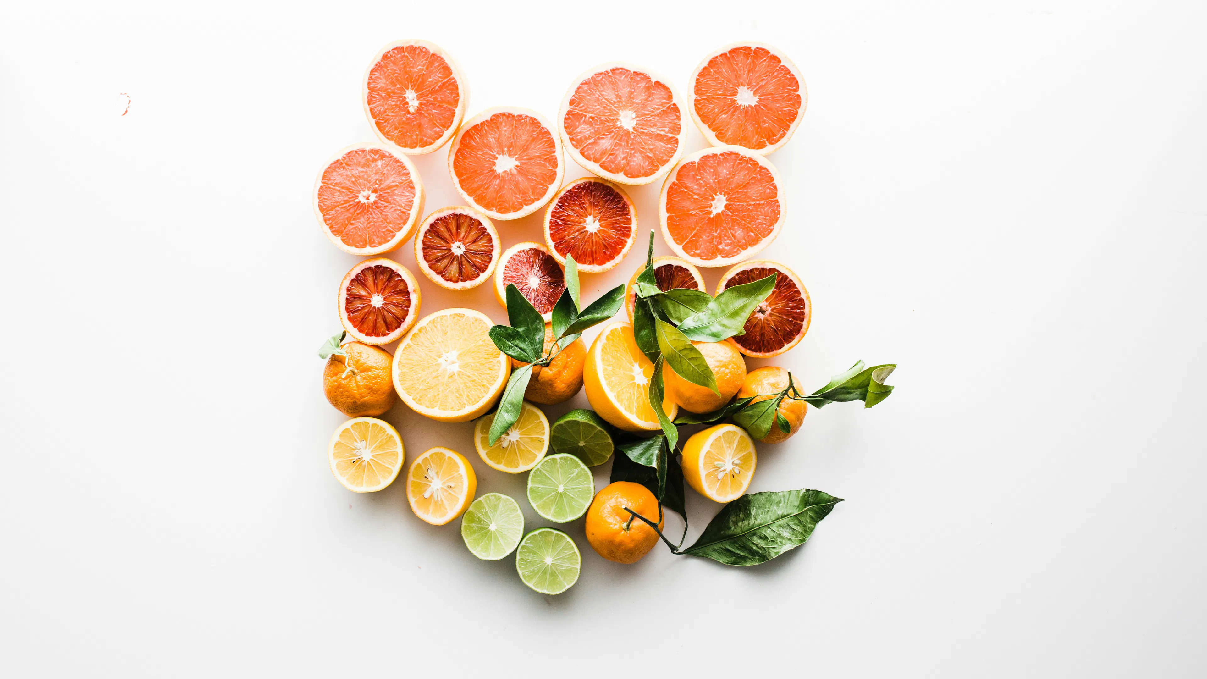 A white table with slices of various colorful citrus fruits arranged in the center