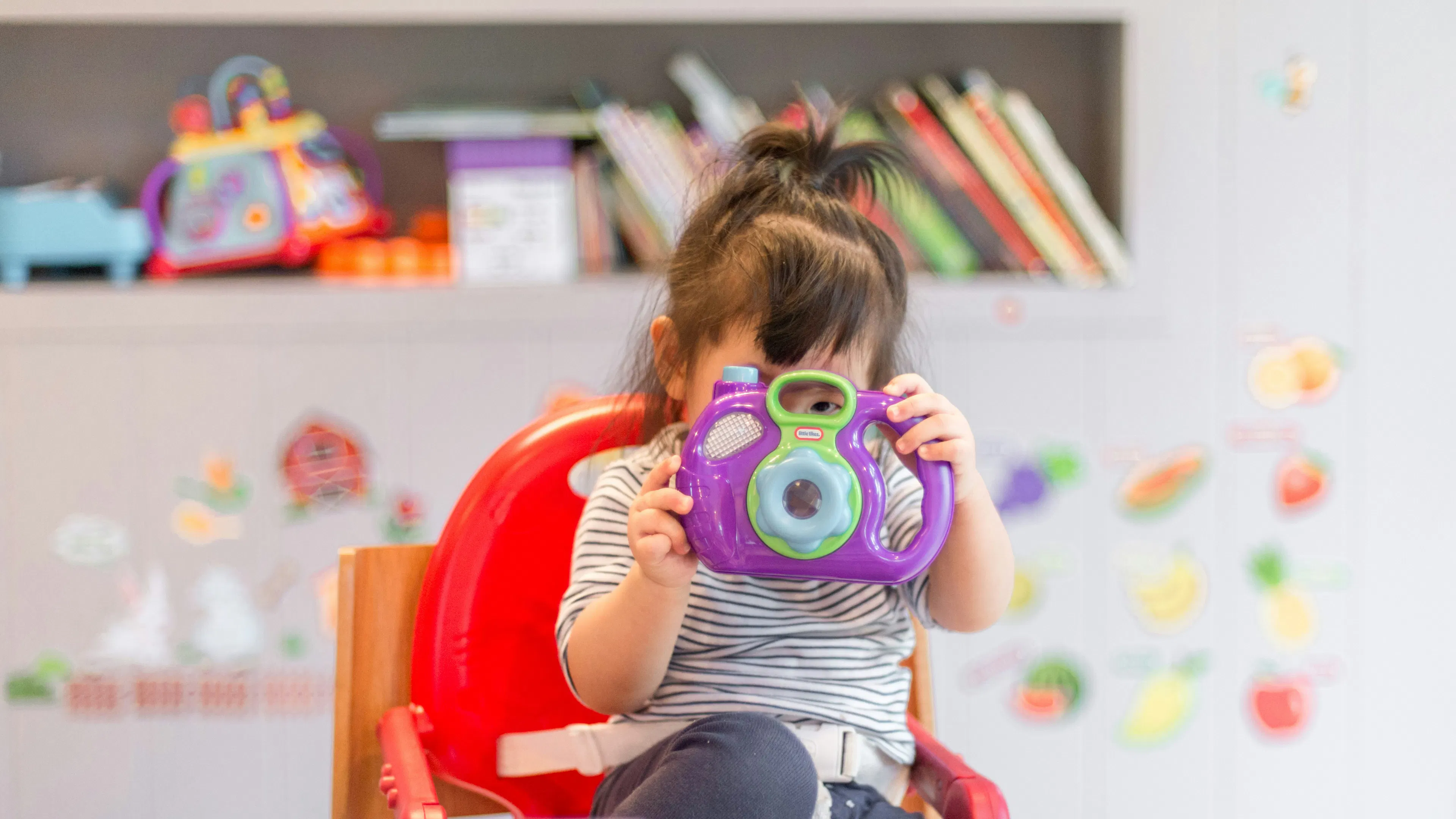 A child playing with a toy camera made of brightly colored plastic