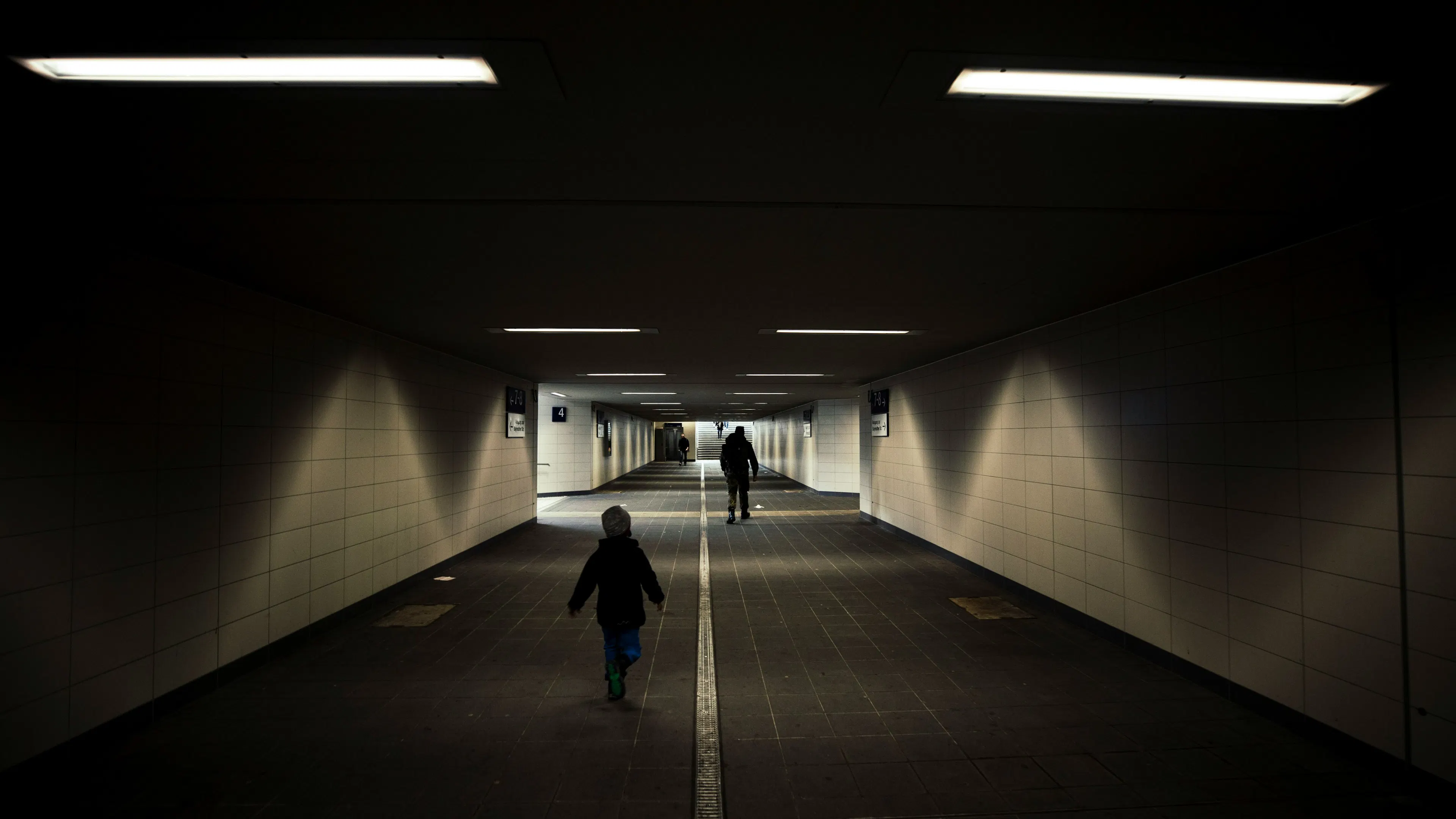 A dimly lit pedestrian tunnel with a few people walking through it