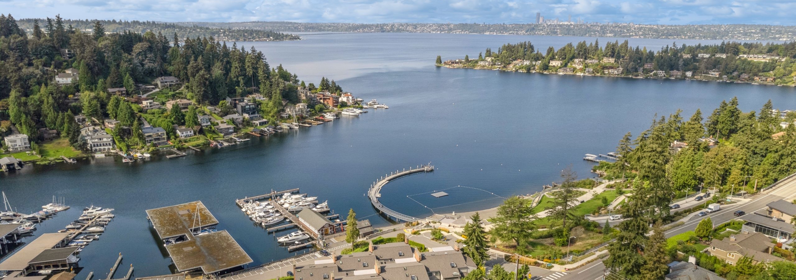 Aerial view of Lake Washington and neighborhood surrounding AMLI Bellevue Park apartments under a bright blue sky with a few clouds