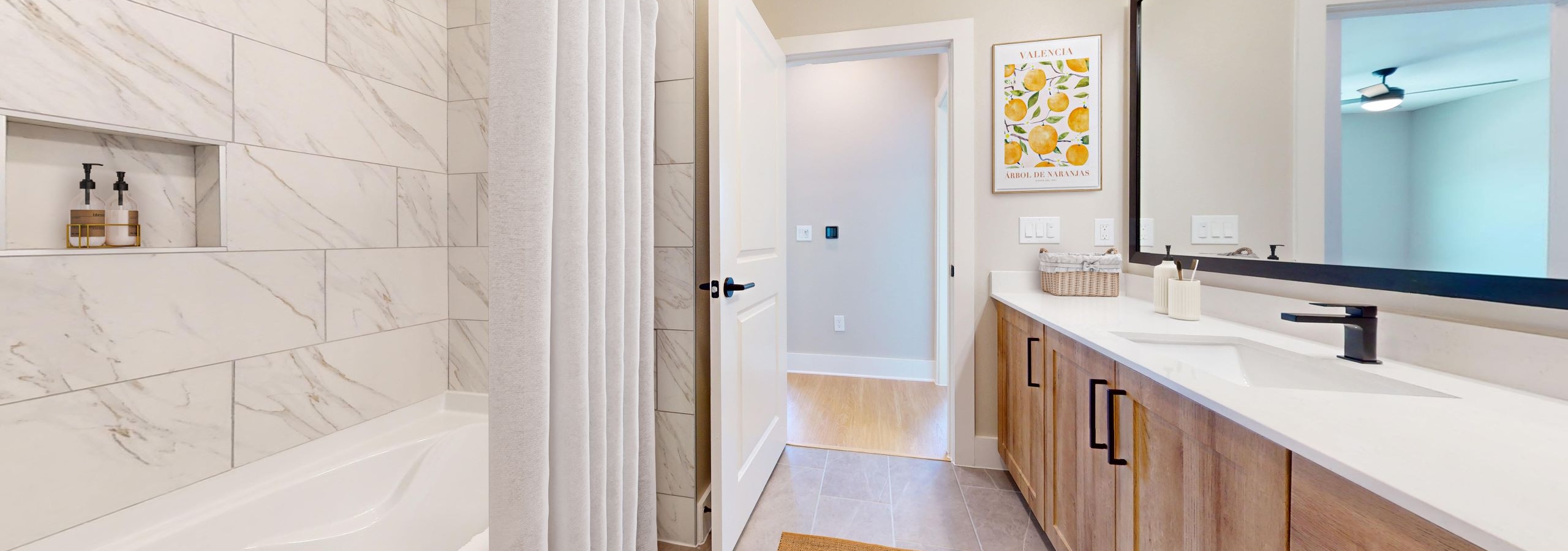 An apartment bathroom at AMLI North Park featuring wooden cabinets with metal handles and an oversized tub surrounded by white tile