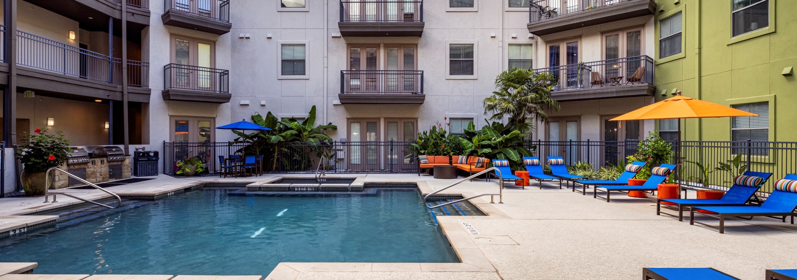 AMLI 300 apartments central courtyard with a swimming pool surrounded by blue lounge chairs and a grill station below building balconies