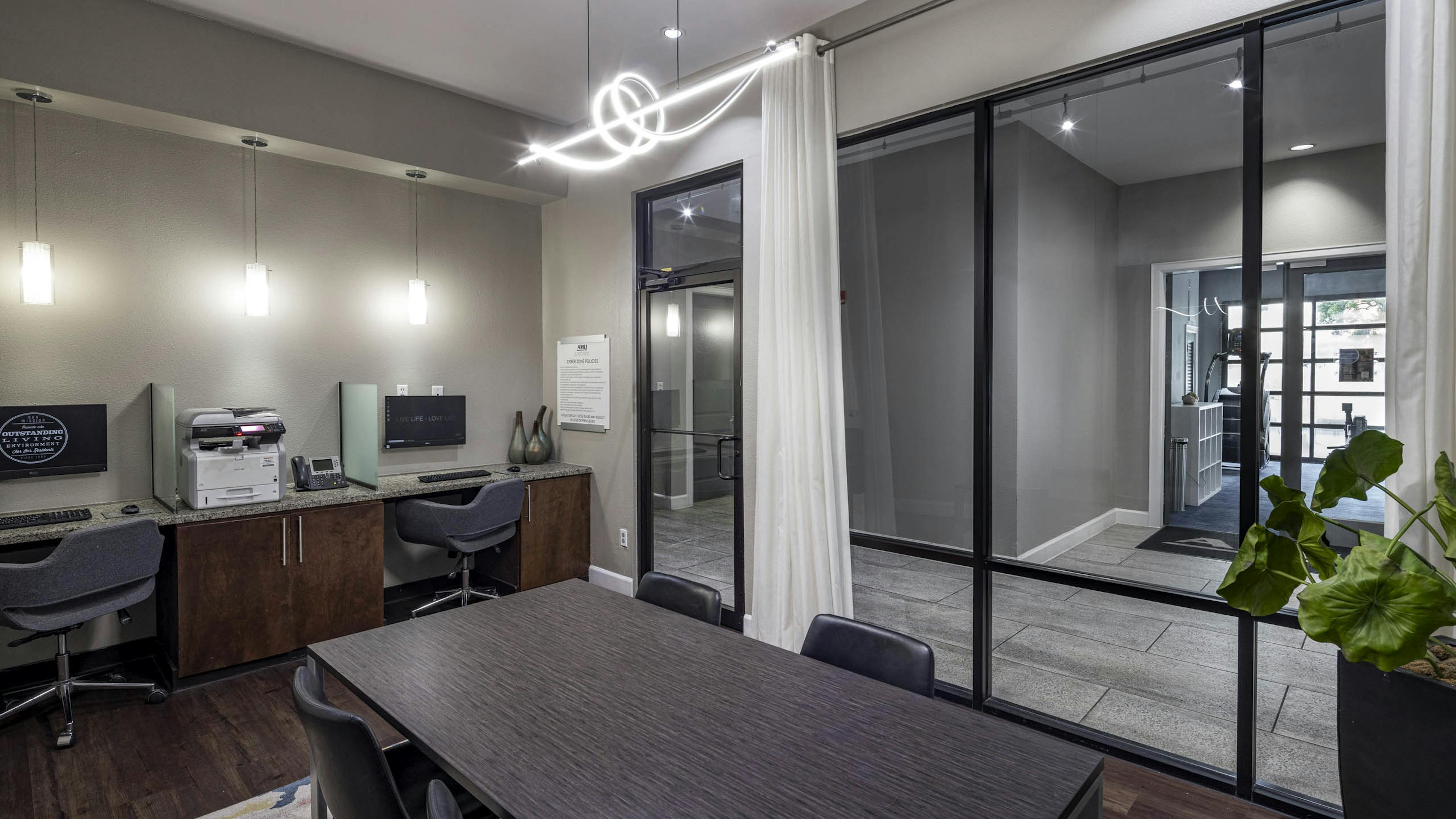 AMLI Eastside apartments business center with a conference table with four chairs, two computer workstations against a wall and a printer