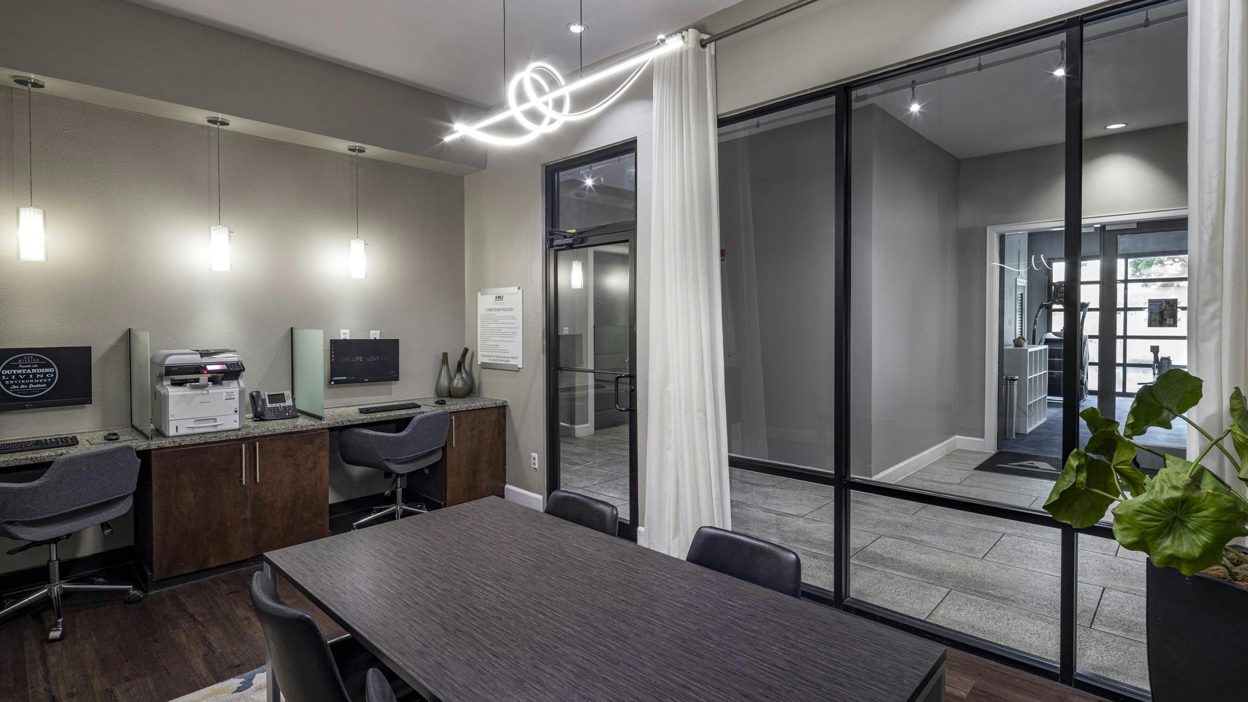 AMLI Eastside apartments business center with a conference table with four chairs, two computer workstations against a wall and a printer